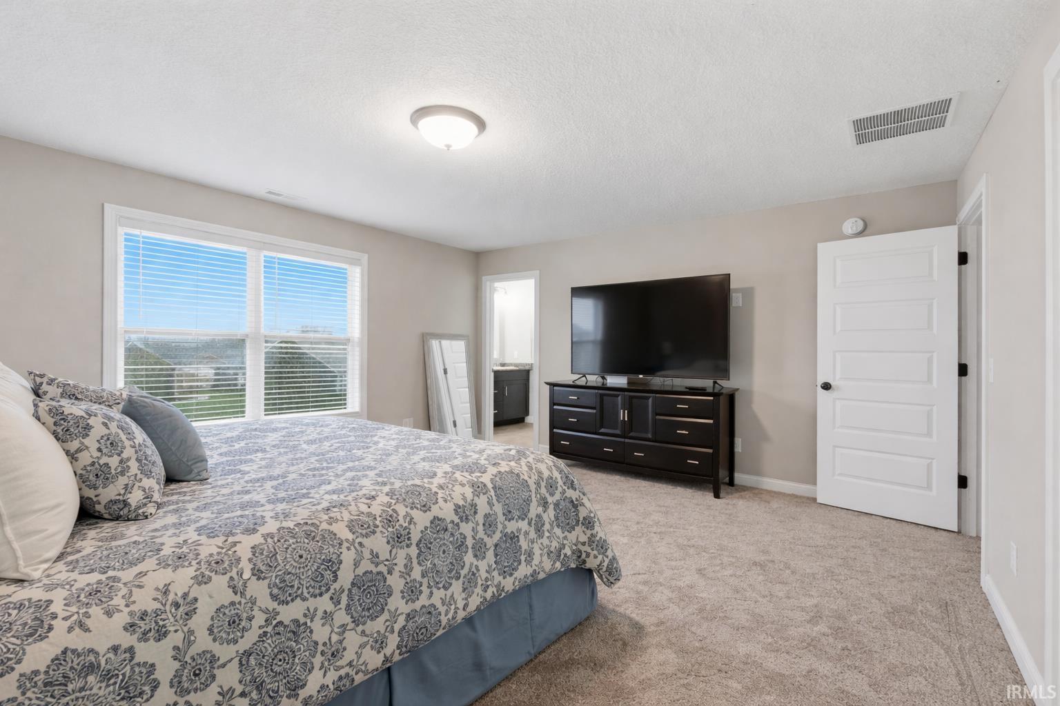 Bedroom featuring light carpet and a textured ceiling