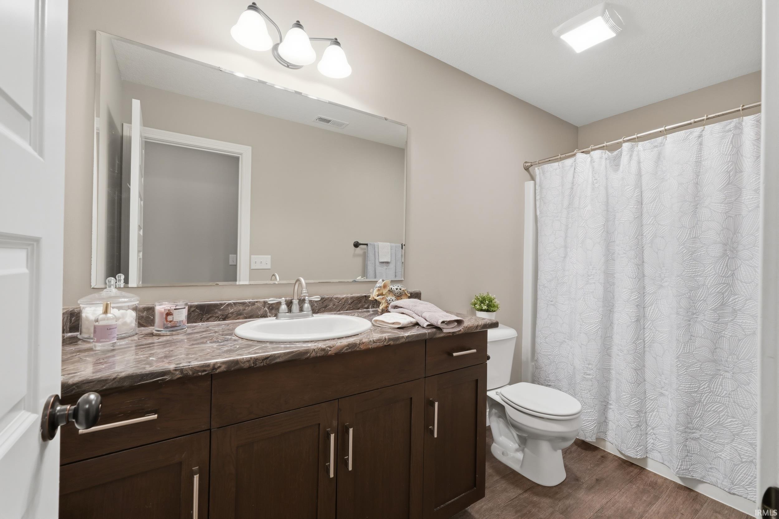 Bathroom featuring vanity, a shower with curtain, and dark wood-type flooring