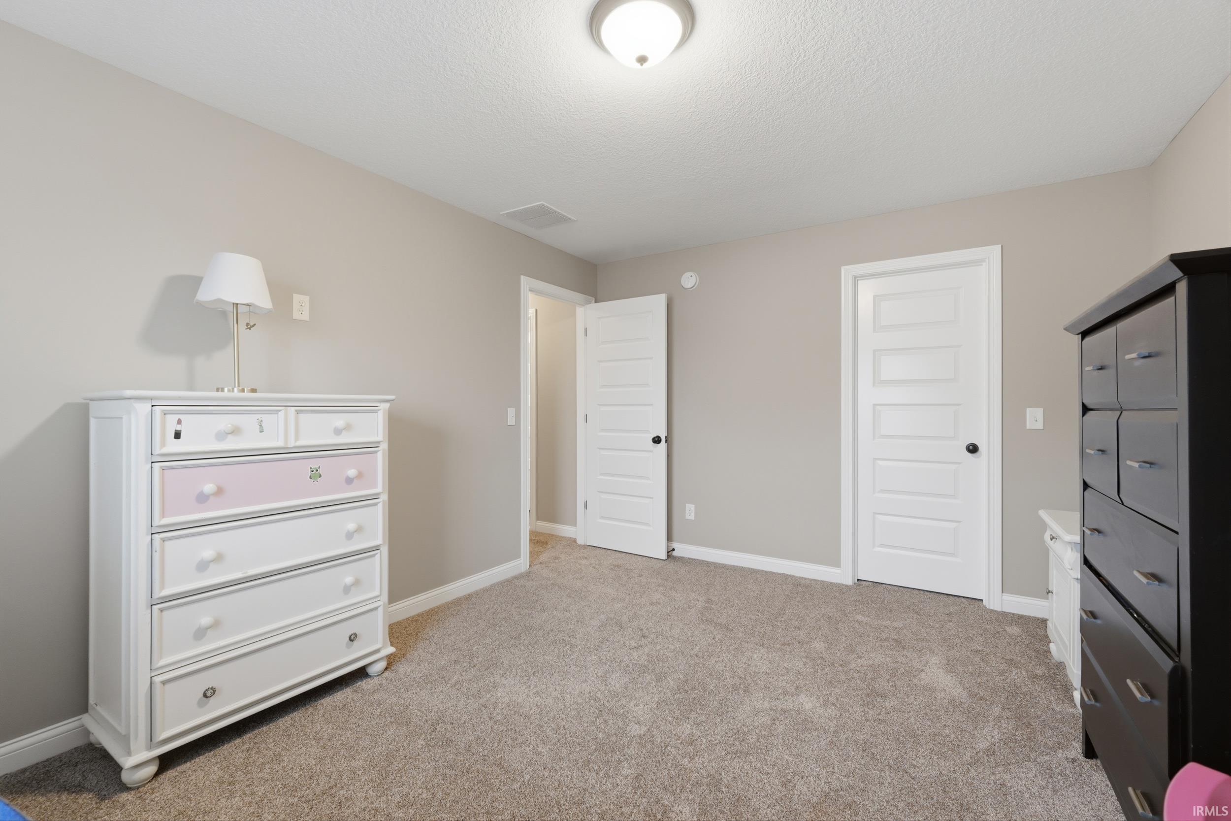 Bedroom with light carpet and a textured ceiling