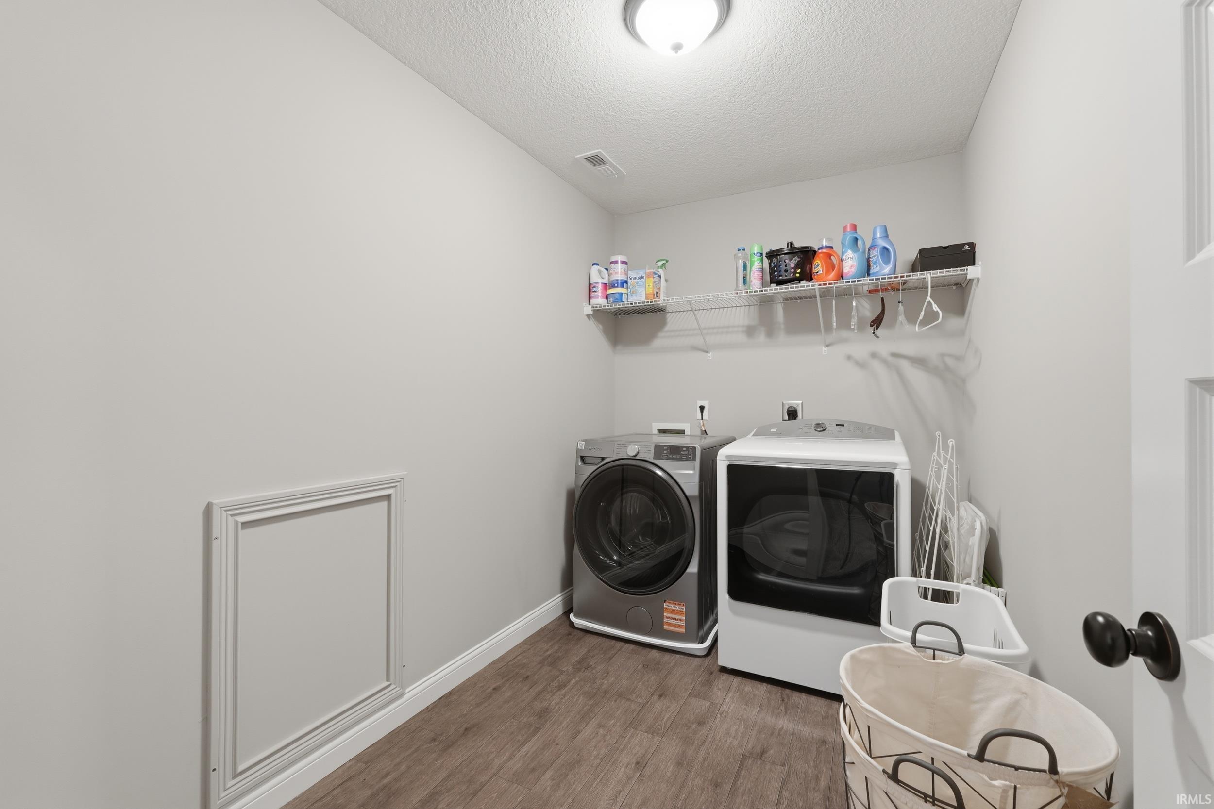 Laundry area with dark wood-style flooring, a textured ceiling, and washer and dryer
