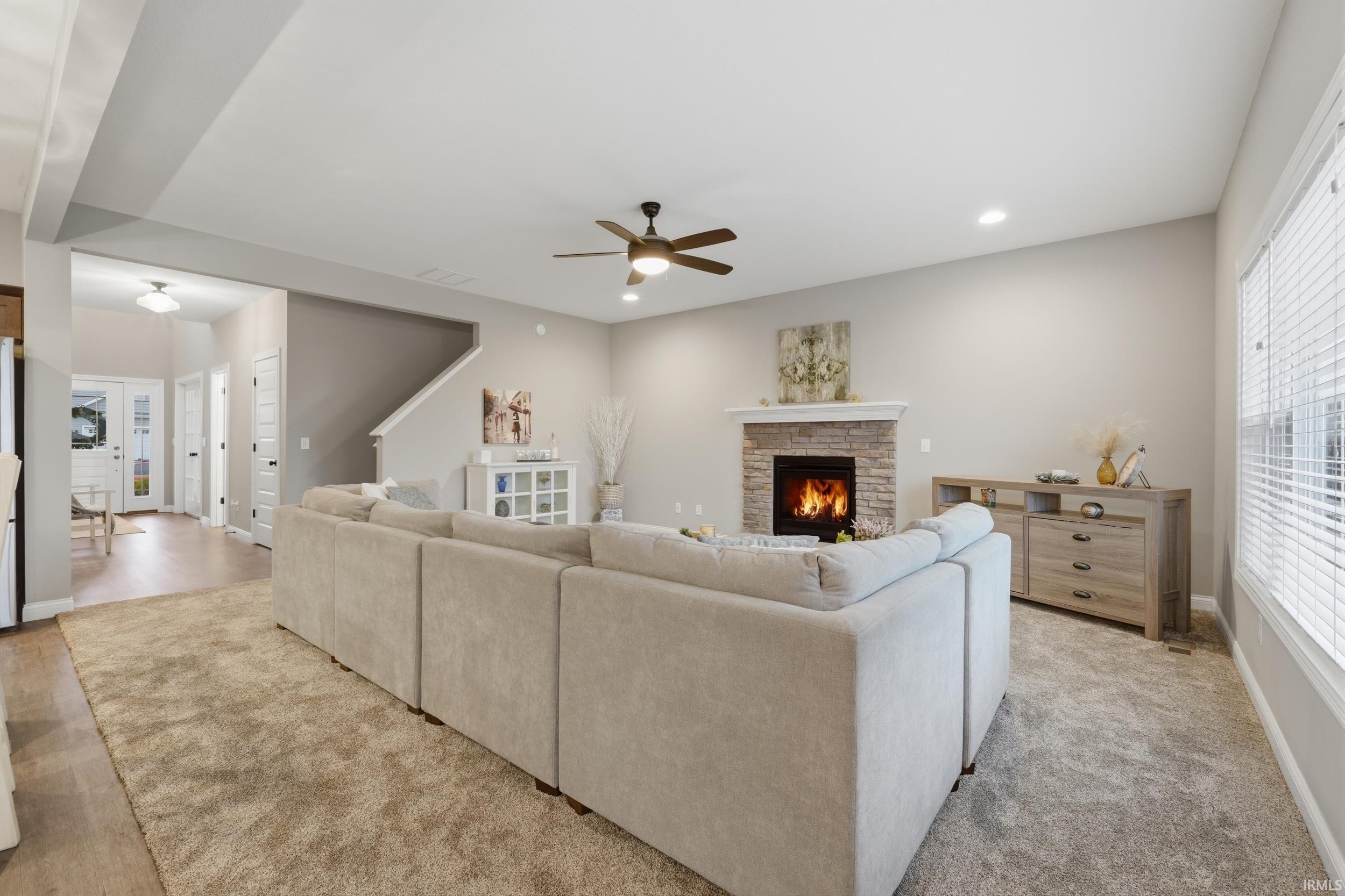 Living room featuring a ceiling fan, a stone fireplace, and recessed lighting