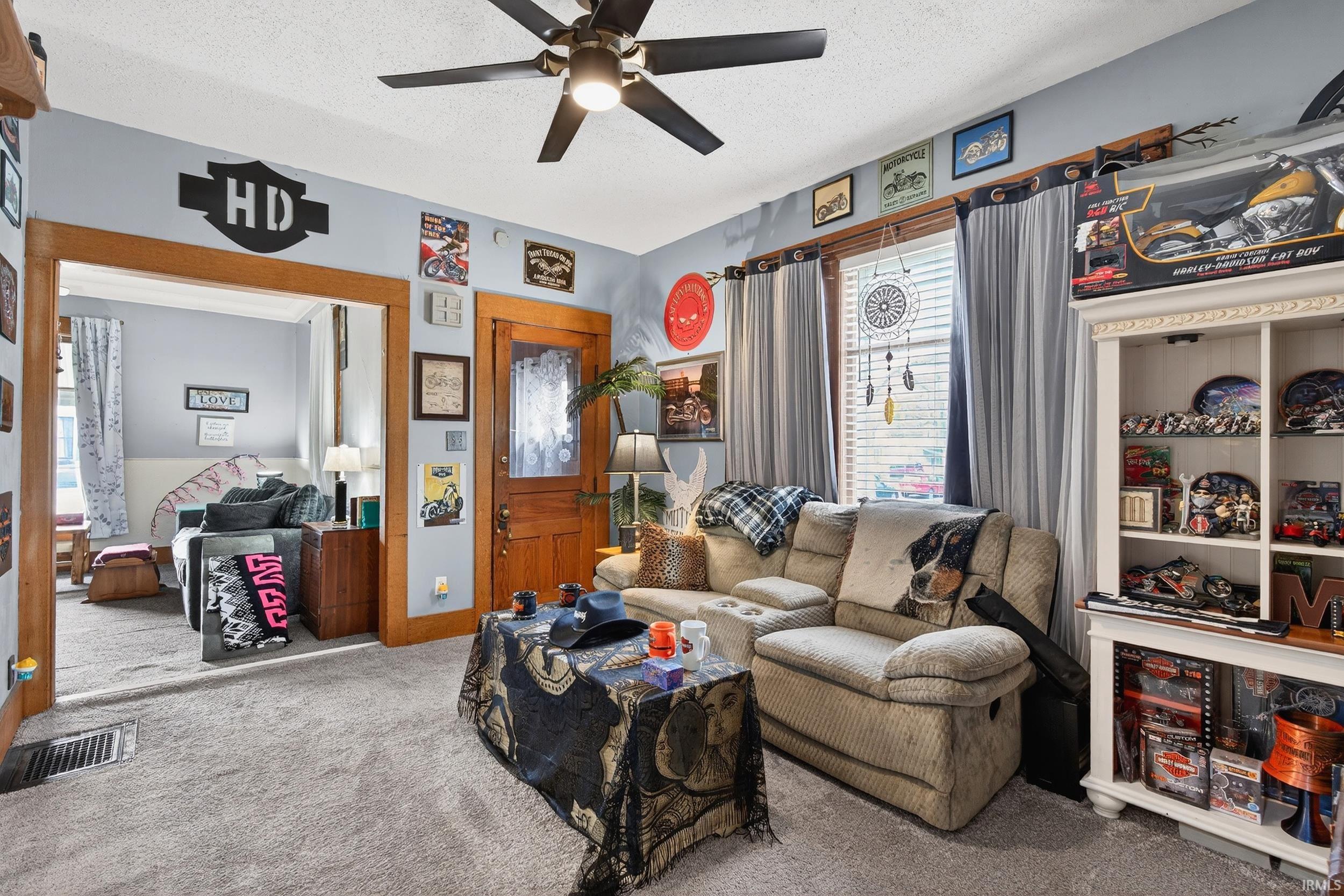 Carpeted living area with a textured ceiling and a ceiling fan