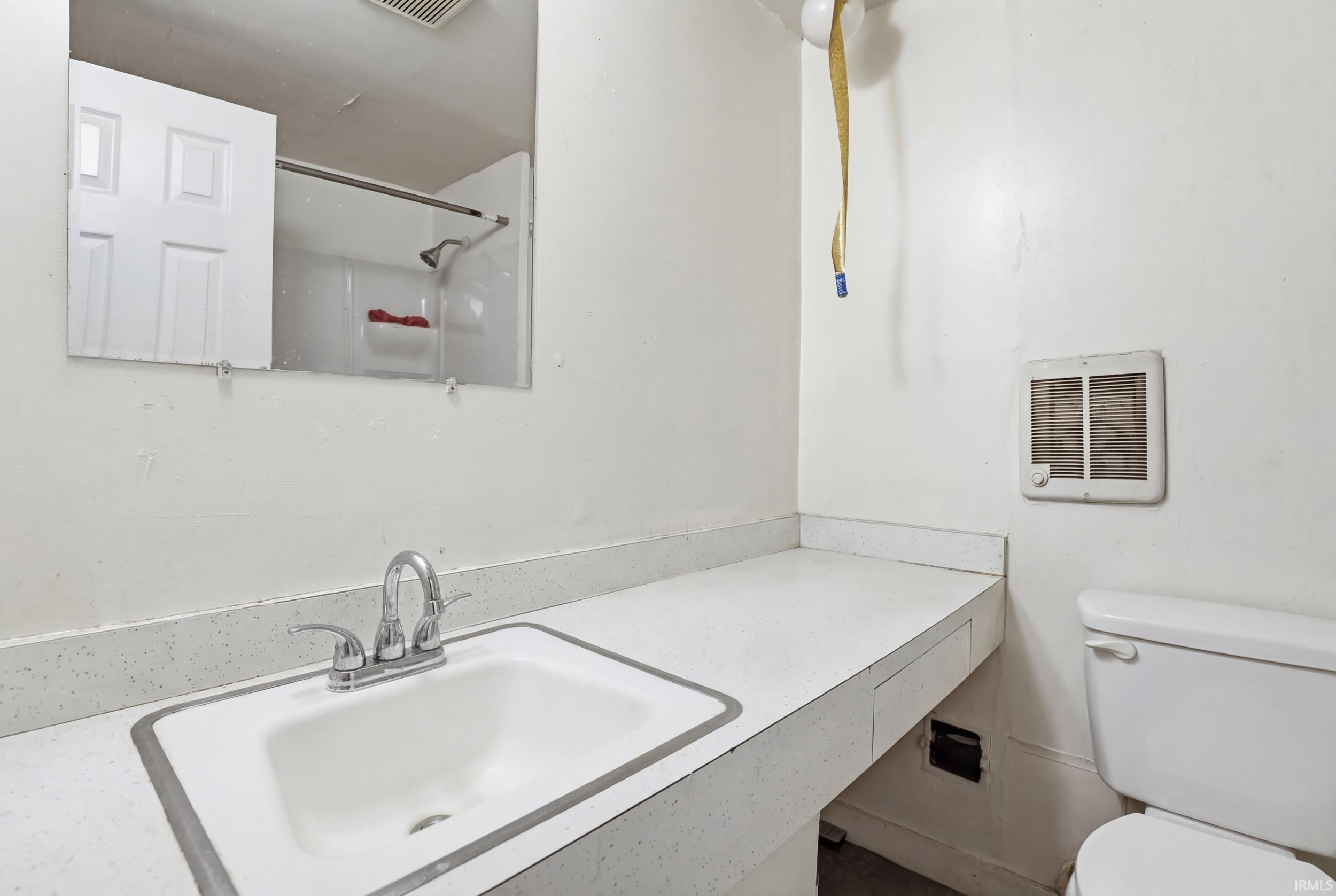 Bathroom with vanity, heating unit, and a shower