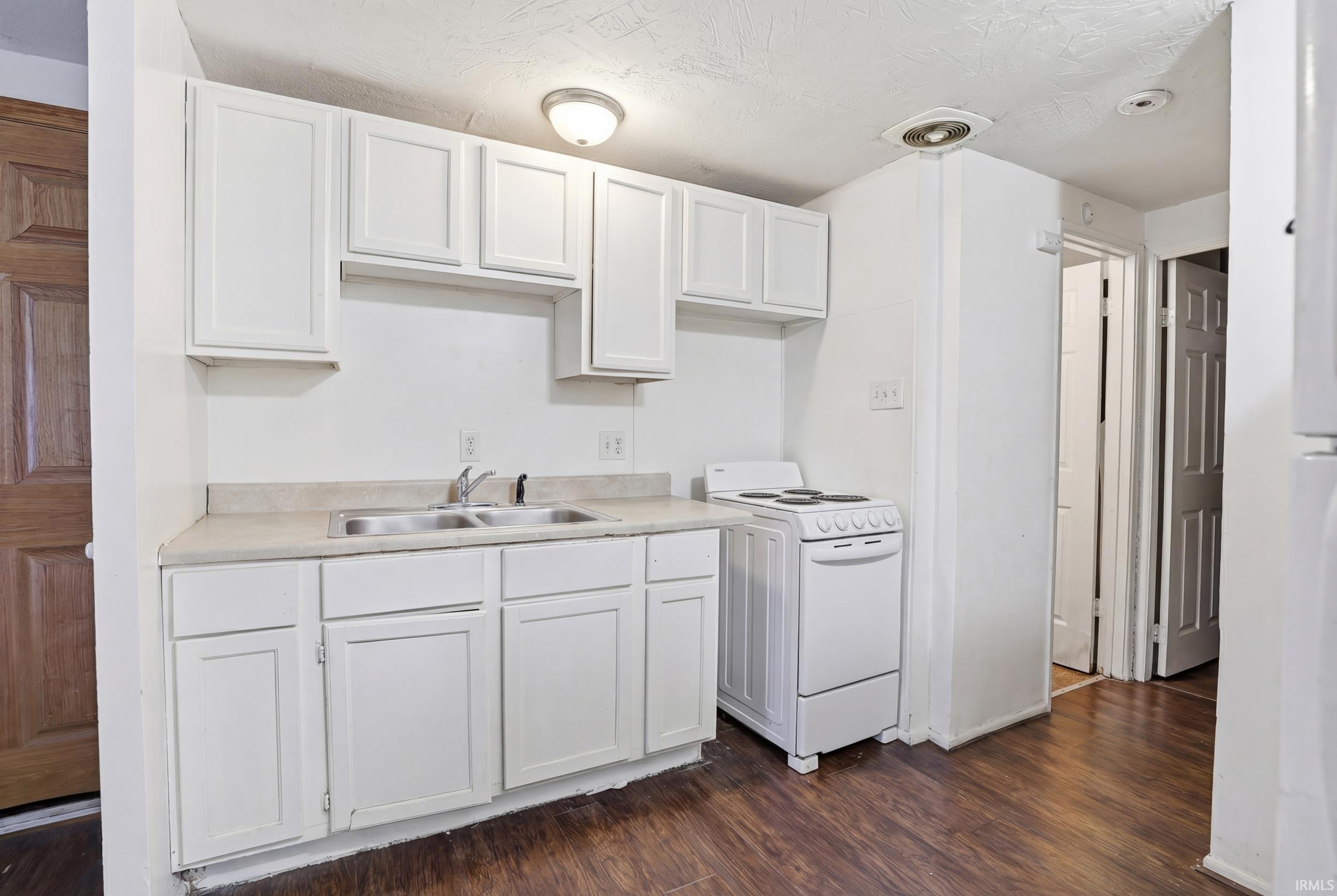 Kitchen featuring light countertops, white cabinetry, dark wood-type flooring, white range with electric cooktop, and a textured ceiling