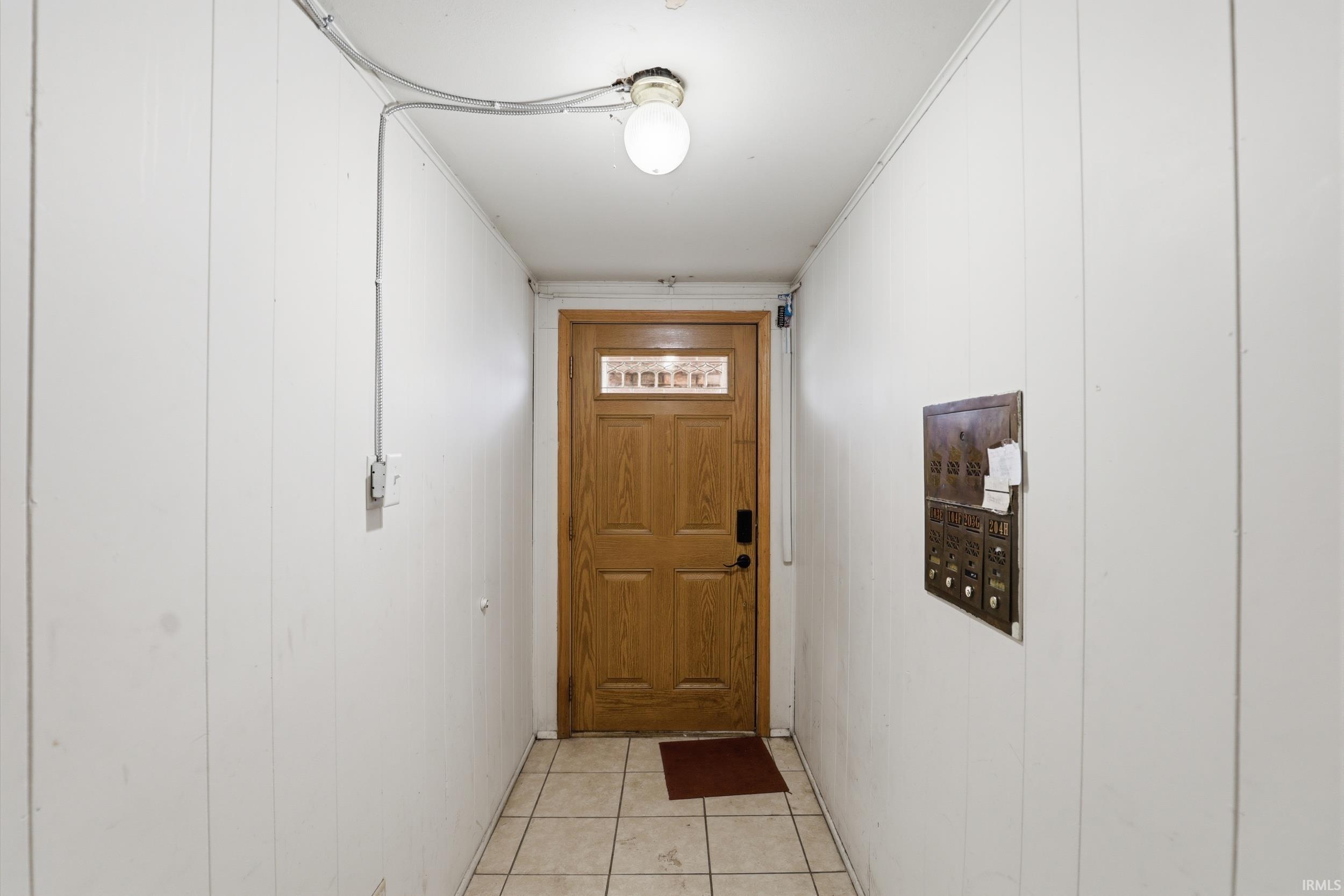 Doorway to outside featuring tile patterned flooring and ornamental molding