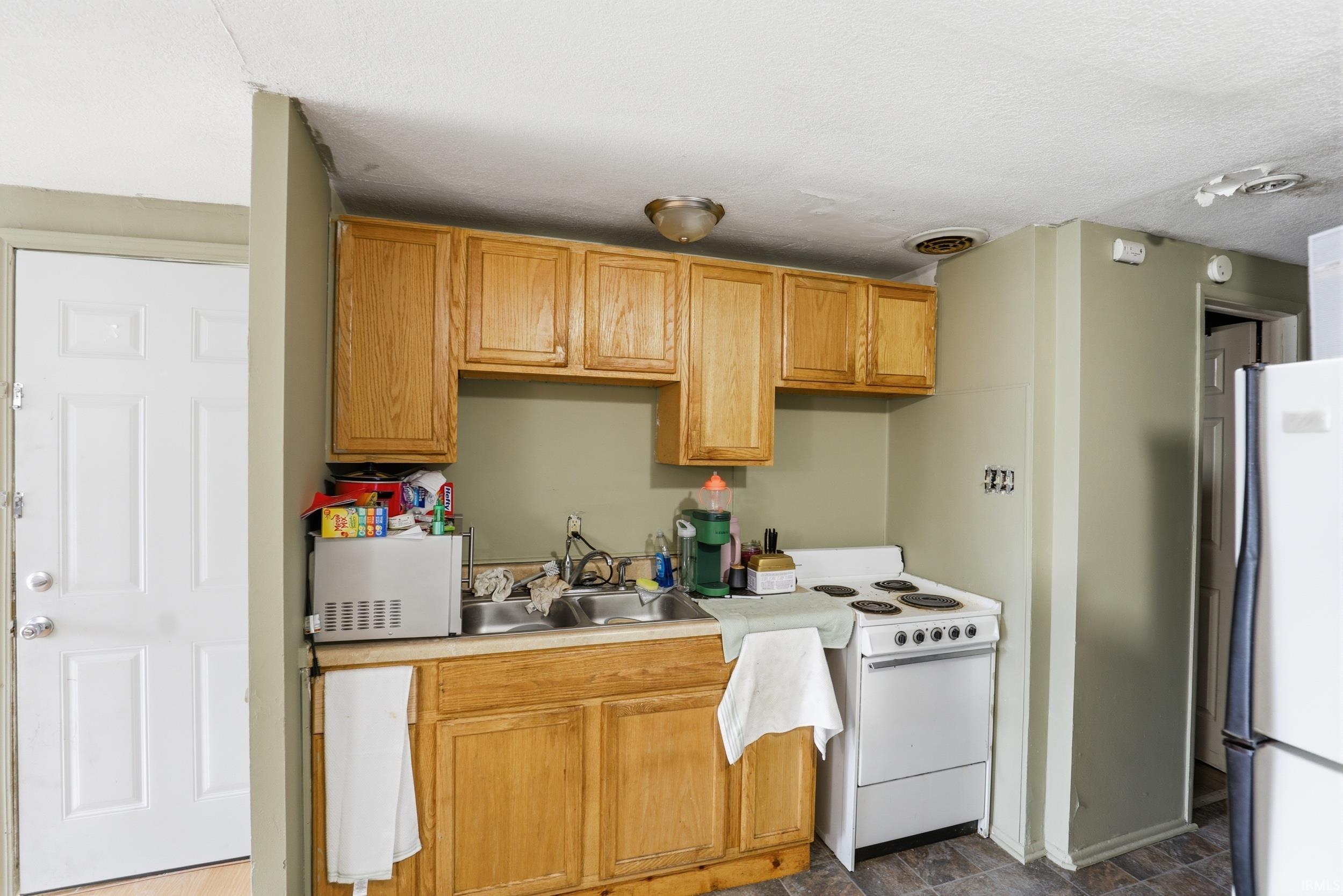 Kitchen featuring white appliances, light countertops, stone finish floors, and a textured ceiling