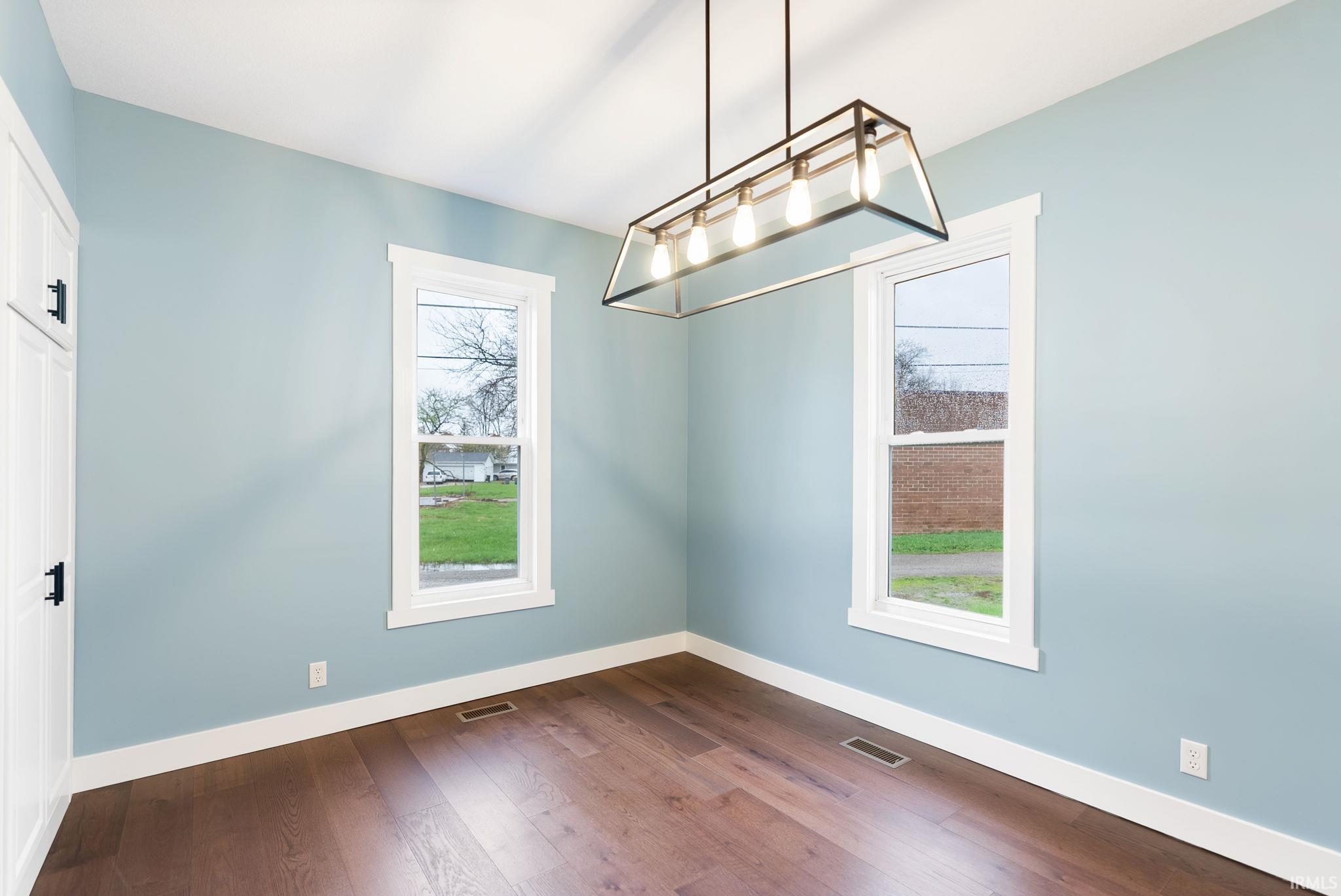 Unfurnished dining area featuring dark wood-type flooring and baseboards