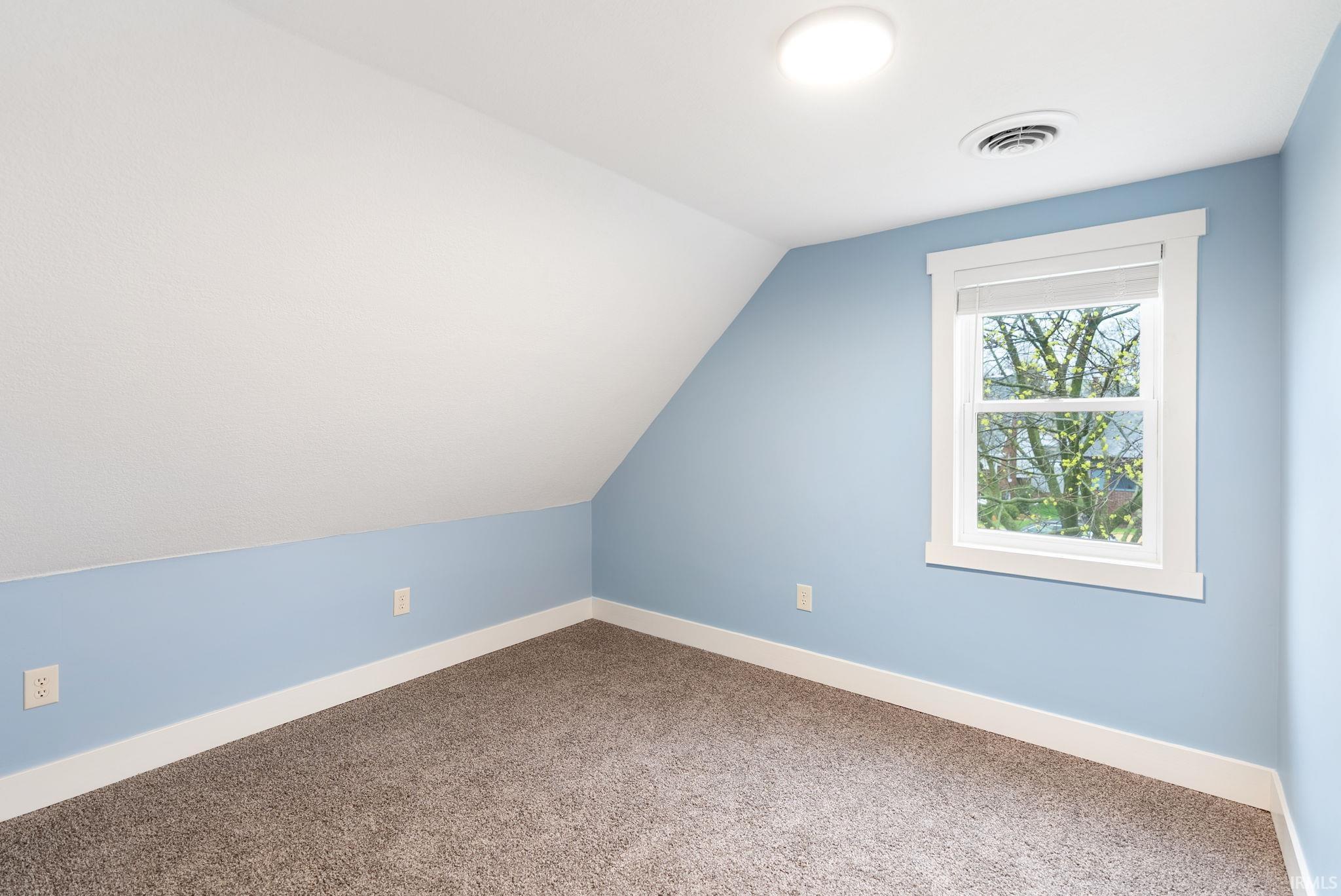 Additional living space with vaulted ceiling and carpet flooring