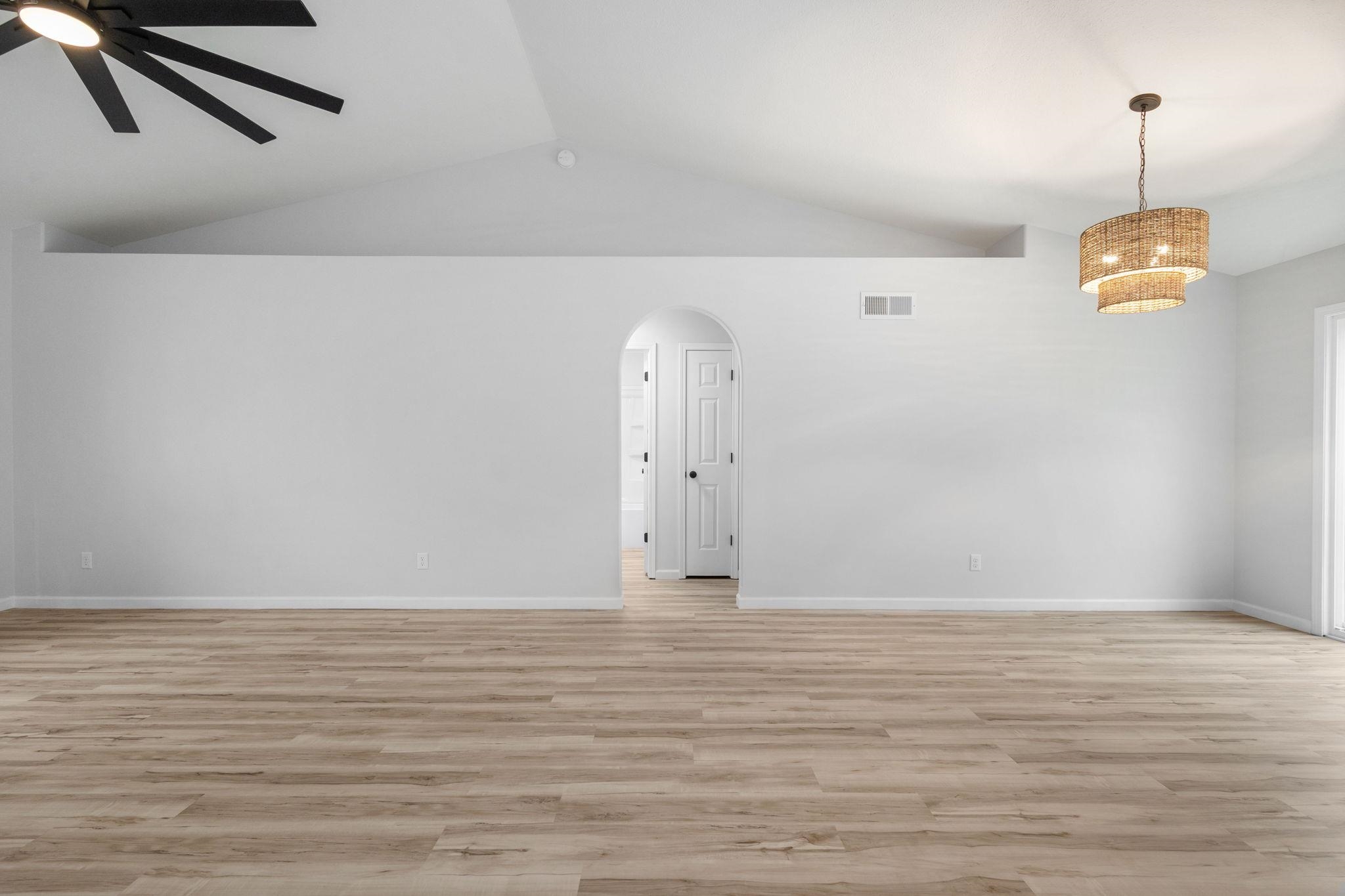 Spare room featuring arched walkways, light wood-style floors, and ceiling fan