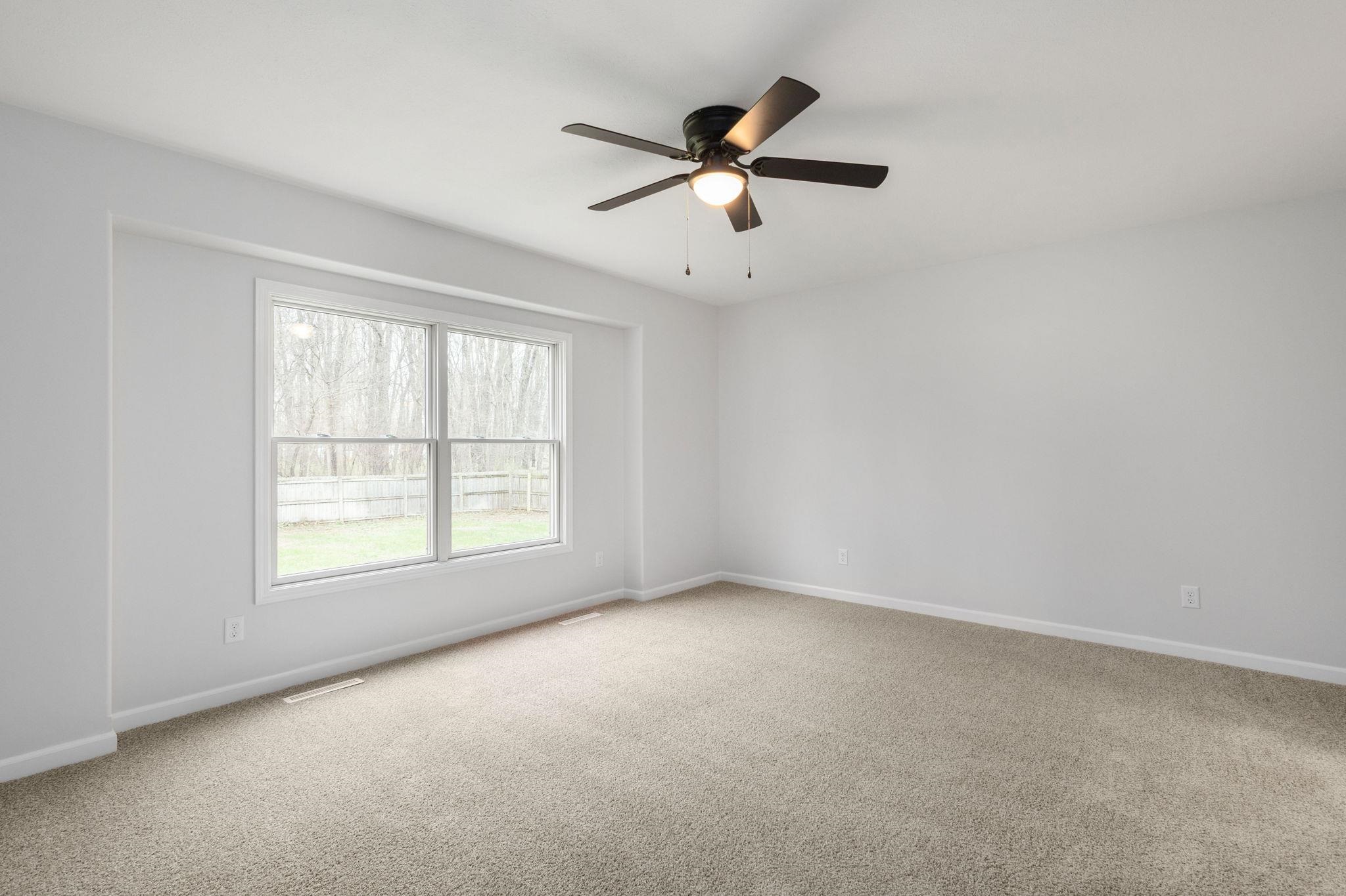 Unfurnished room with light colored carpet and a ceiling fan