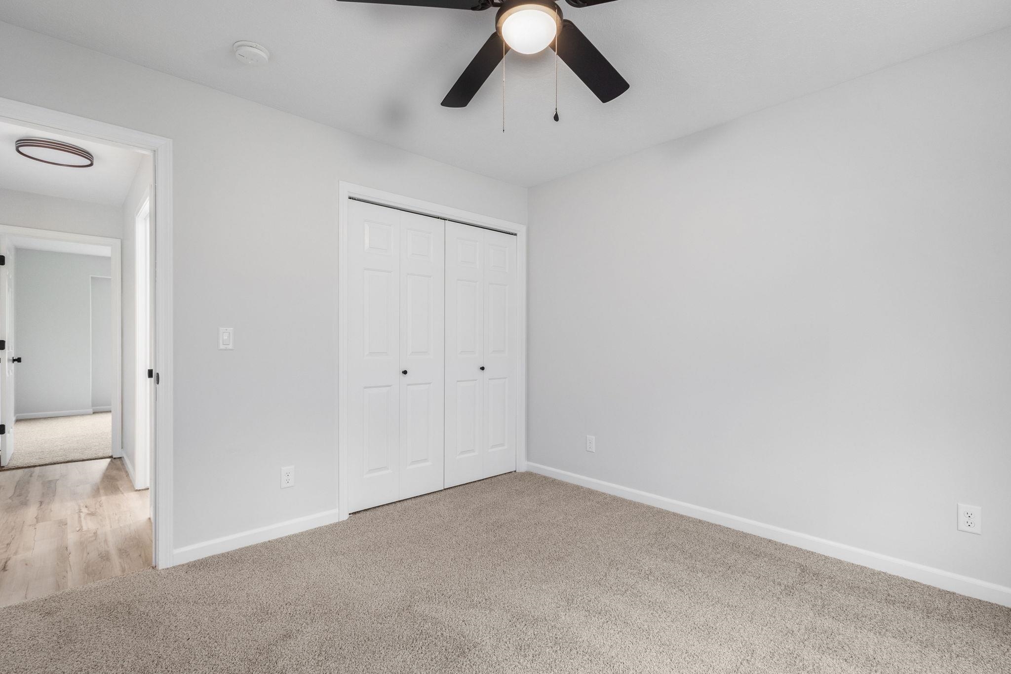 Unfurnished bedroom with light carpet, a closet, and ceiling fan