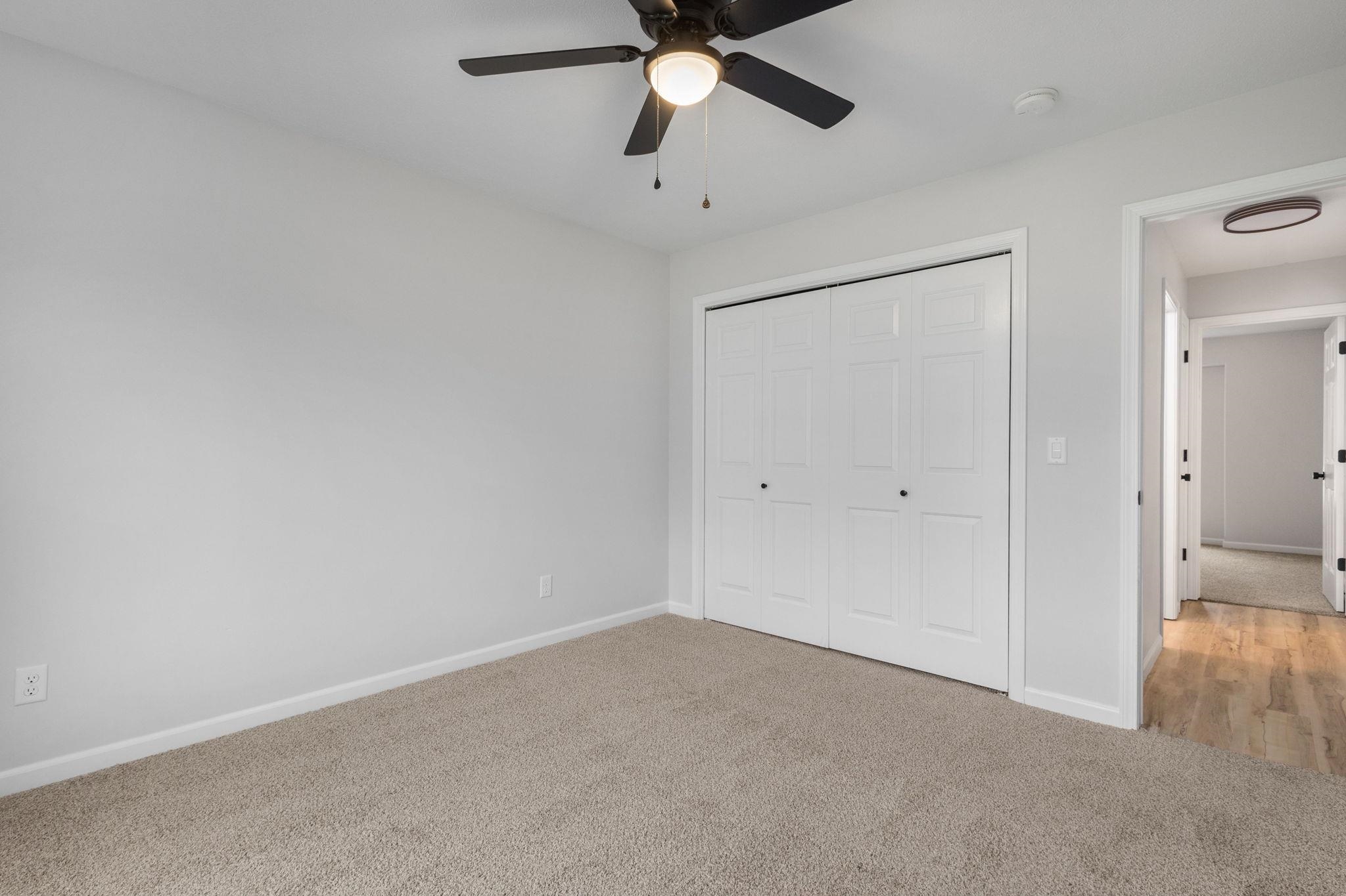 Unfurnished bedroom featuring light carpet, a closet, and a ceiling fan
