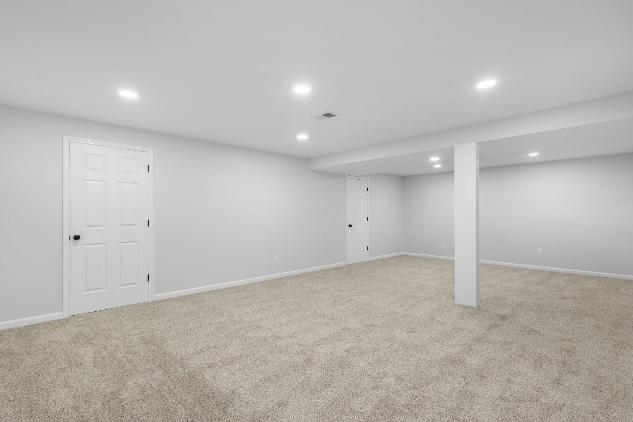 Finished below grade area with light colored carpet and recessed lighting