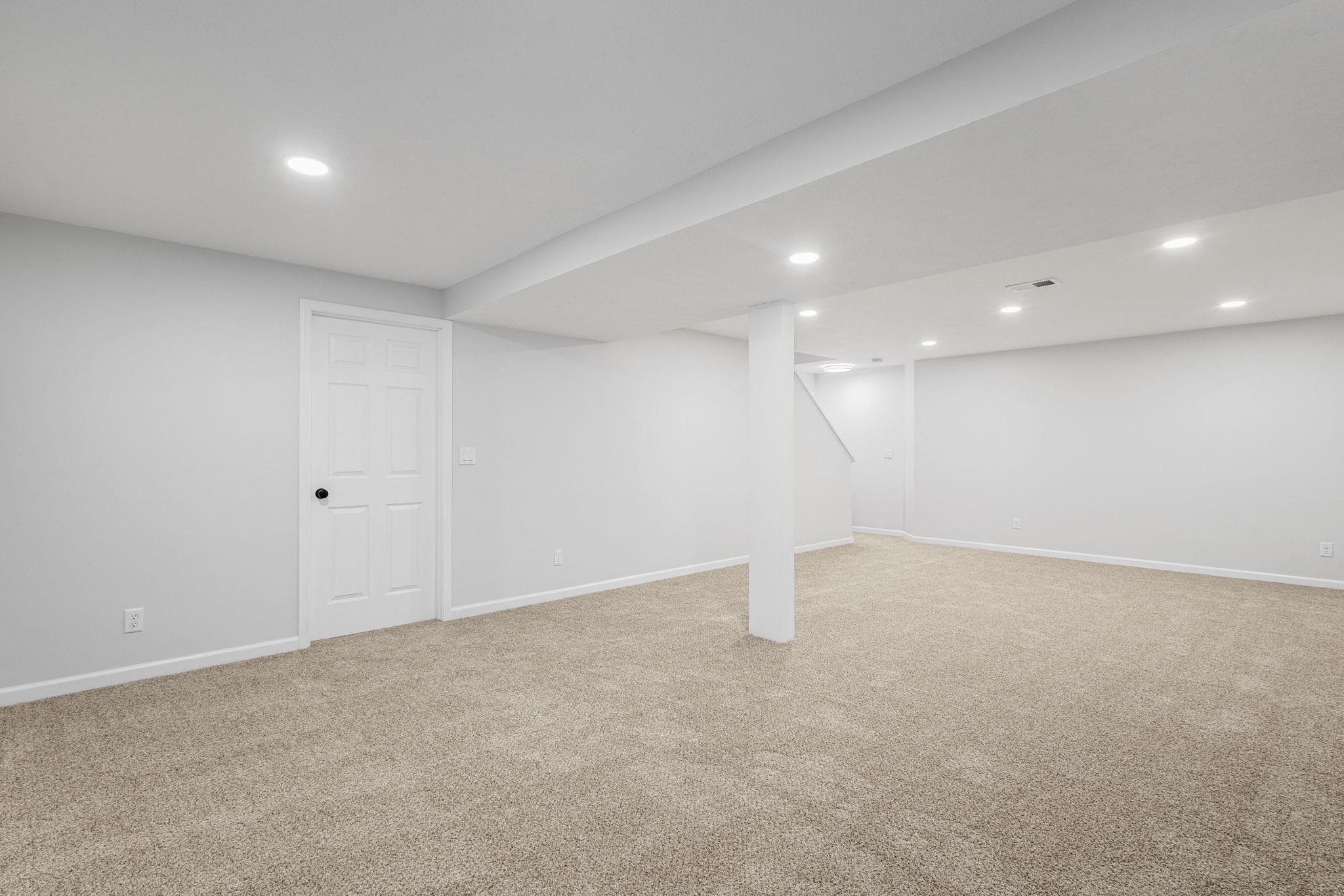 Finished below grade area with light colored carpet and recessed lighting