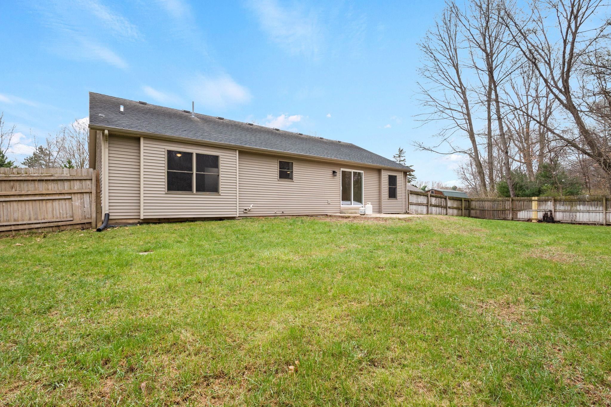 Rear view of property with a fenced backyard and roof with shingles