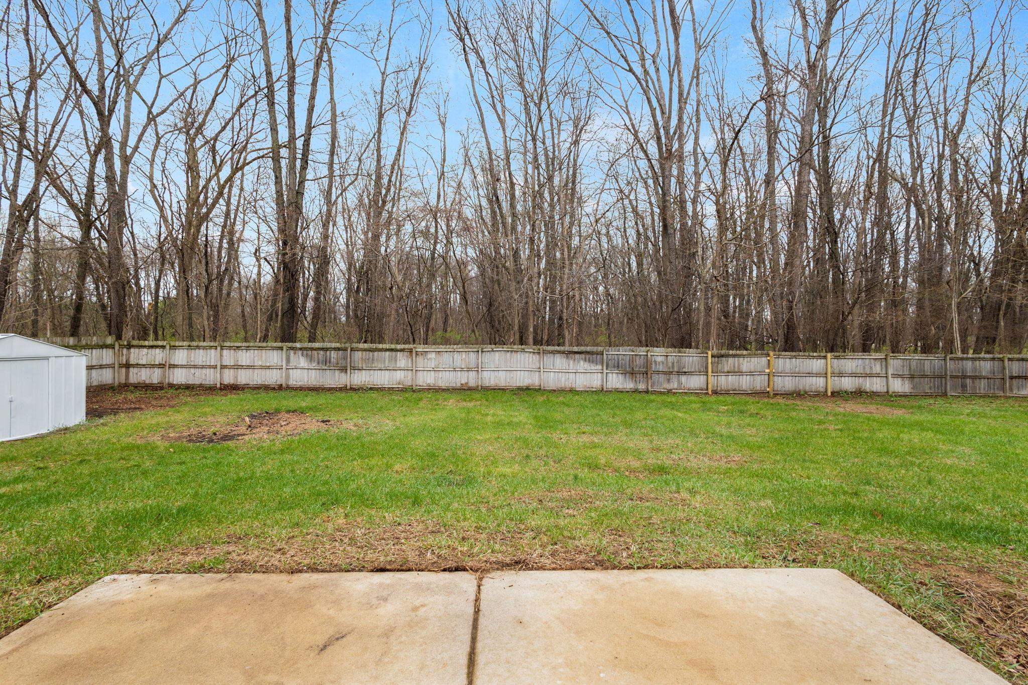 Fenced backyard with a storage shed and a patio