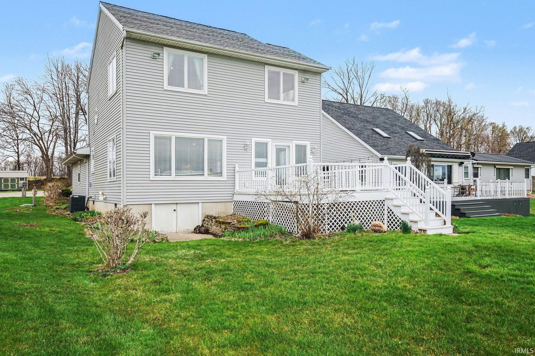 Rear view of property featuring a lawn, a shingled roof, and a deck
