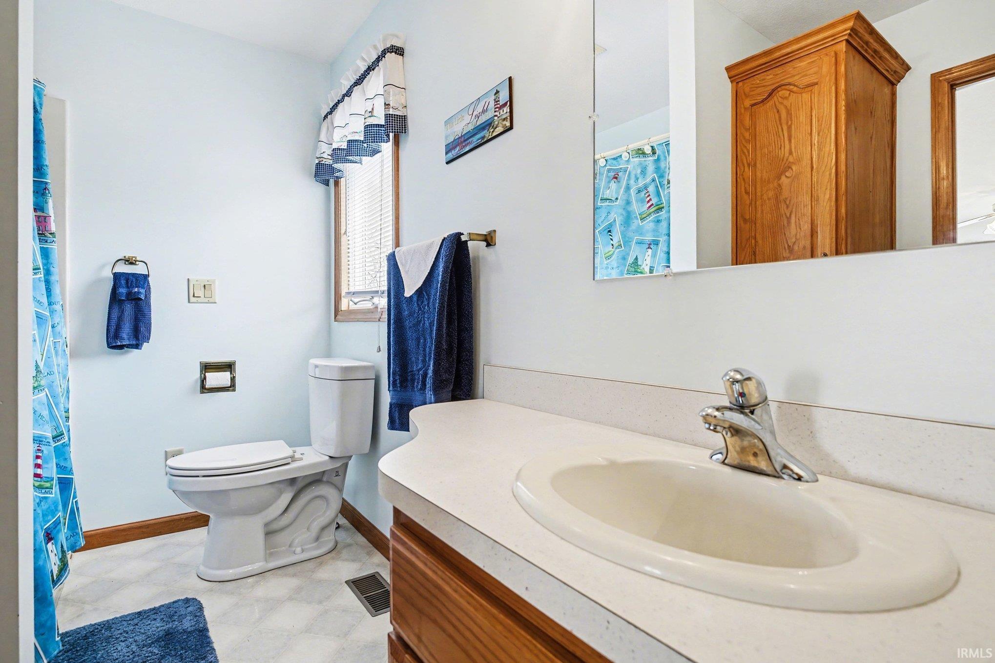 Full bathroom featuring a shower with shower curtain, light flooring, and vanity