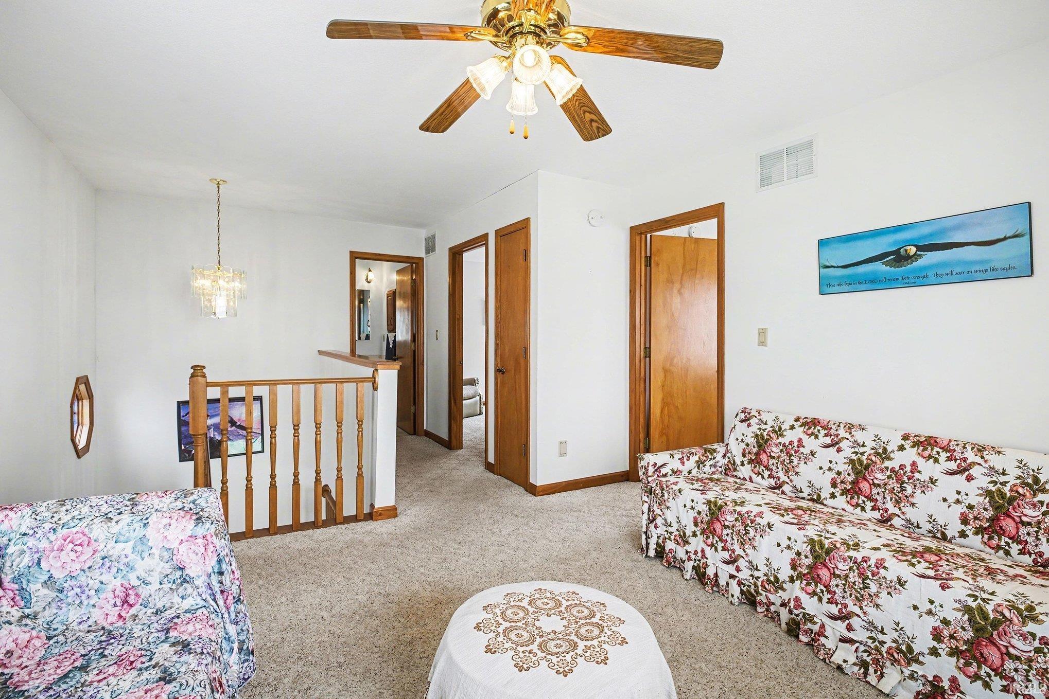 Sitting area featuring light carpet, a ceiling fan, and a chandelier