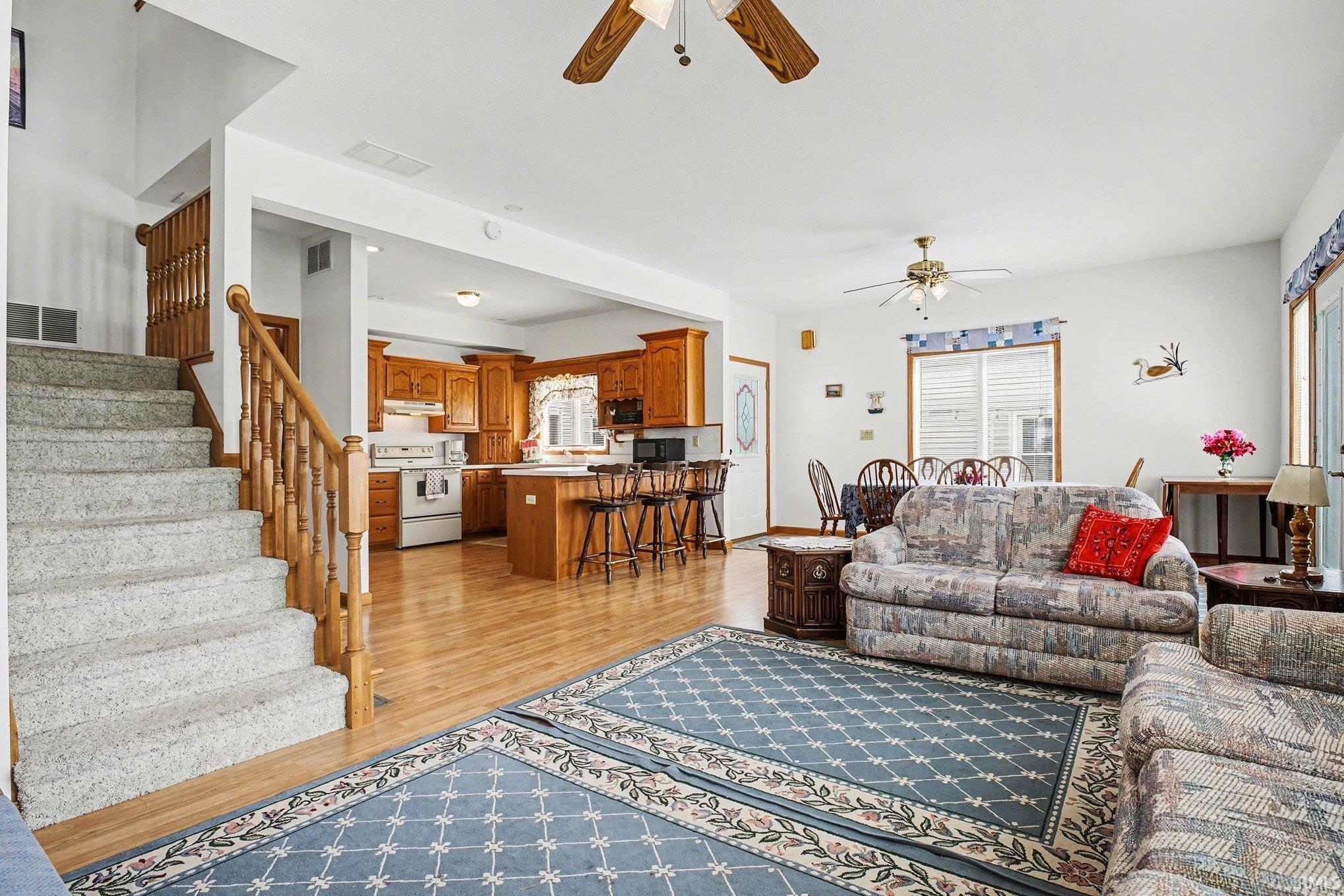 Living room featuring light wood-style flooring, ceiling fan, and healthy amount of natural light