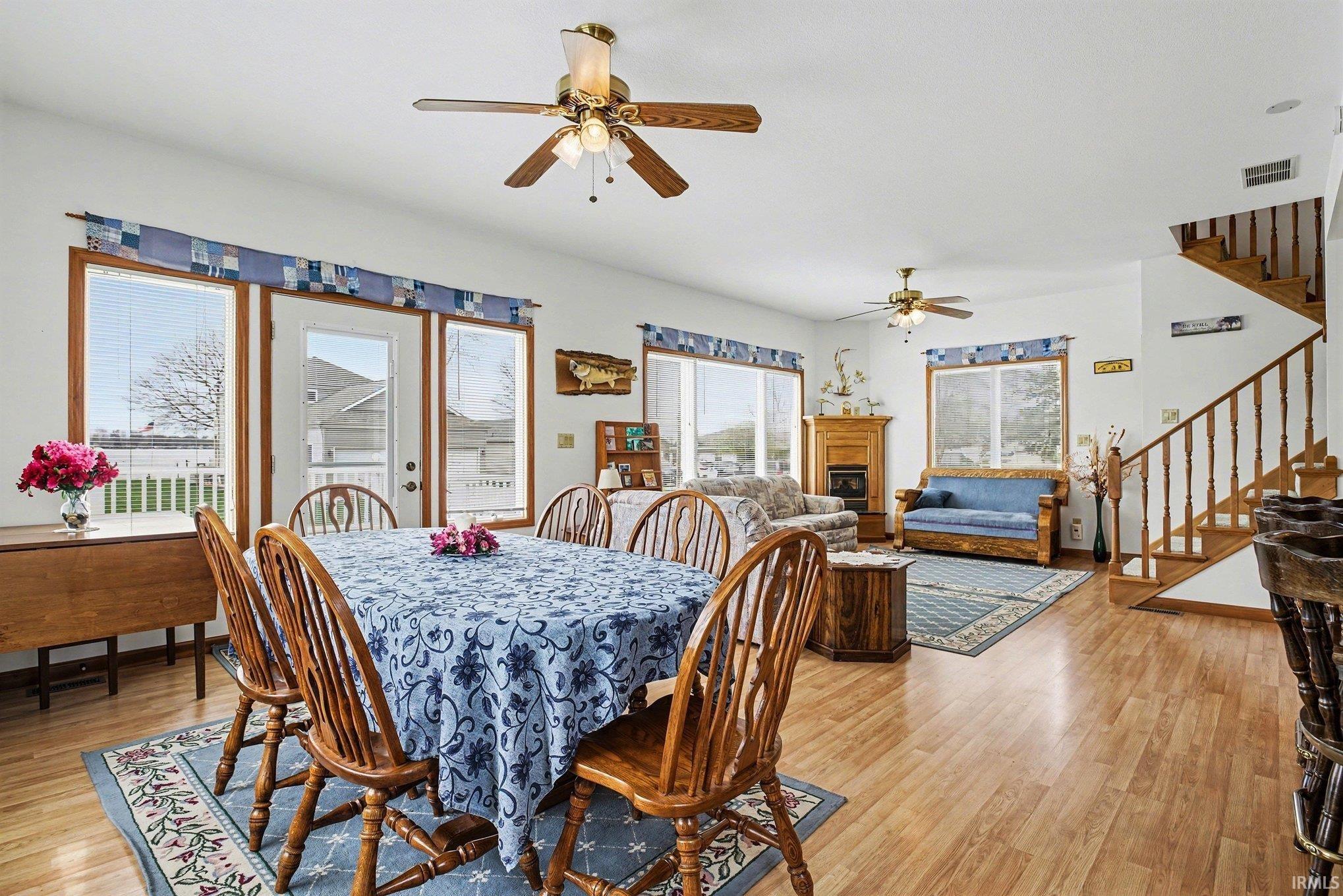 Dining room with light wood-style floors, a fireplace, and ceiling fan