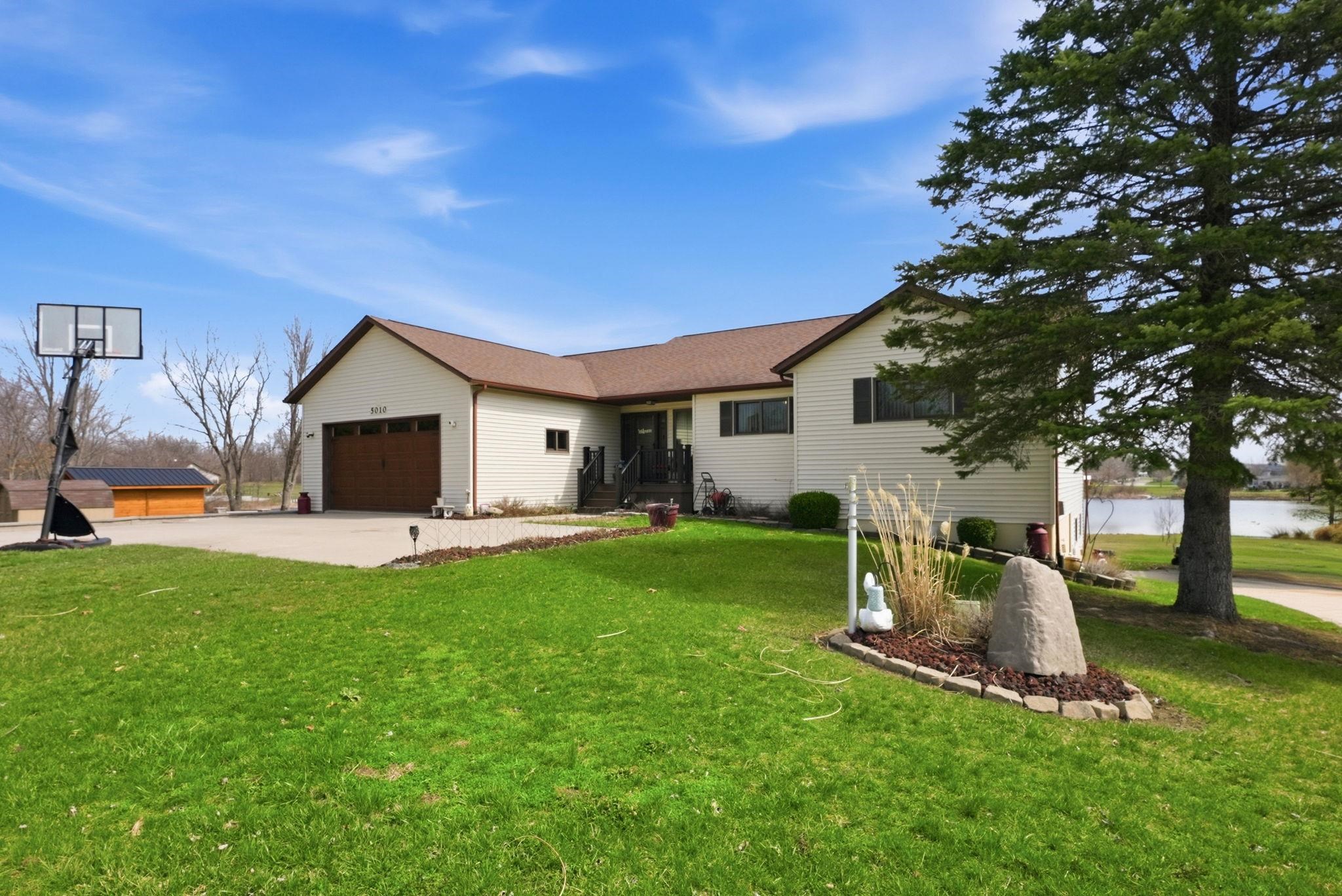 Single story home with an attached garage, a front yard, and driveway