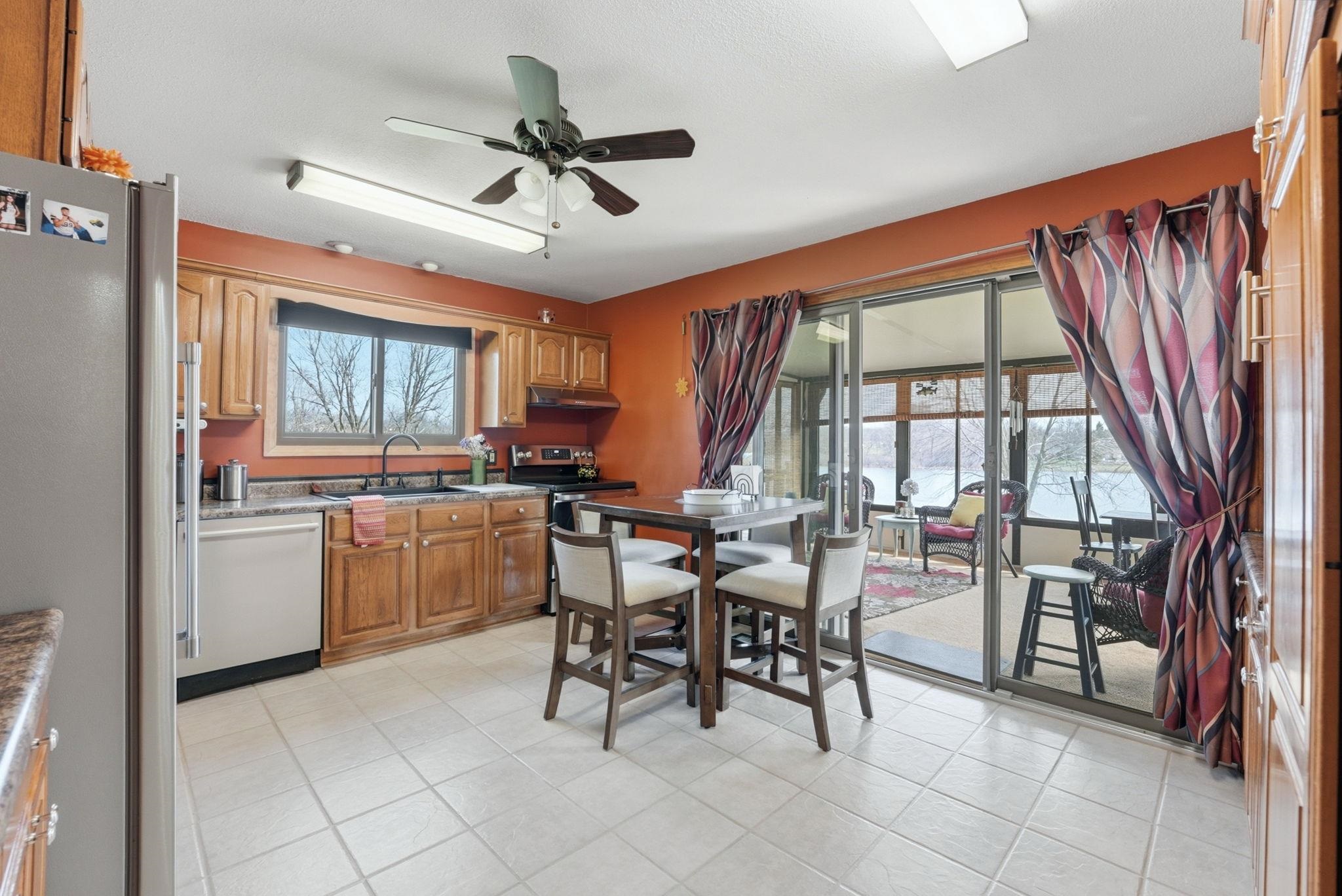 Kitchen featuring stainless steel appliances, wood finish cabinetry, a ceiling fan, and light tile patterned floors