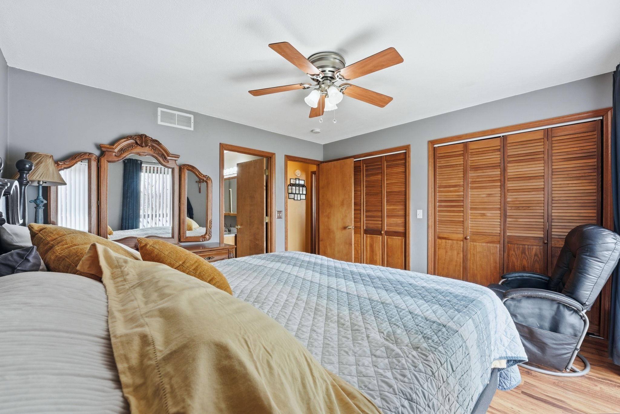 Bedroom featuring two closets, wood finished floors, and a ceiling fan
