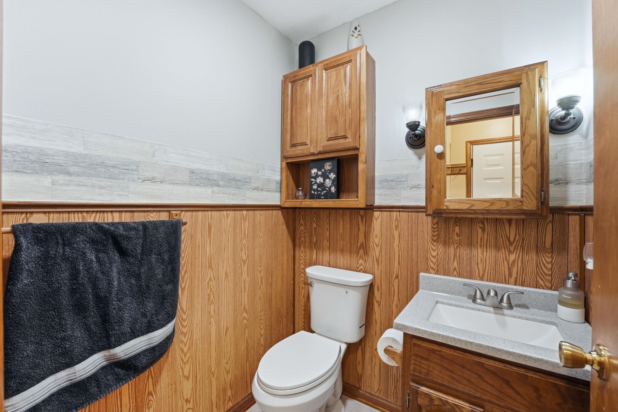 Half bath featuring wainscoting, vanity, and wooden walls