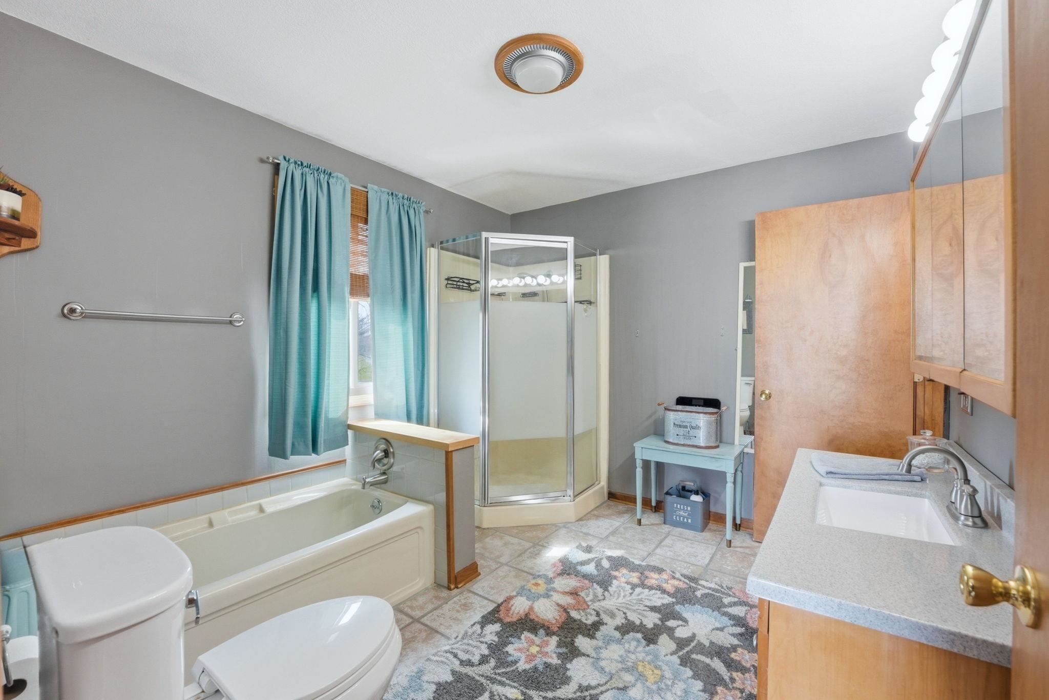 Bathroom featuring vanity, a bath, a shower stall, and light tile patterned floors