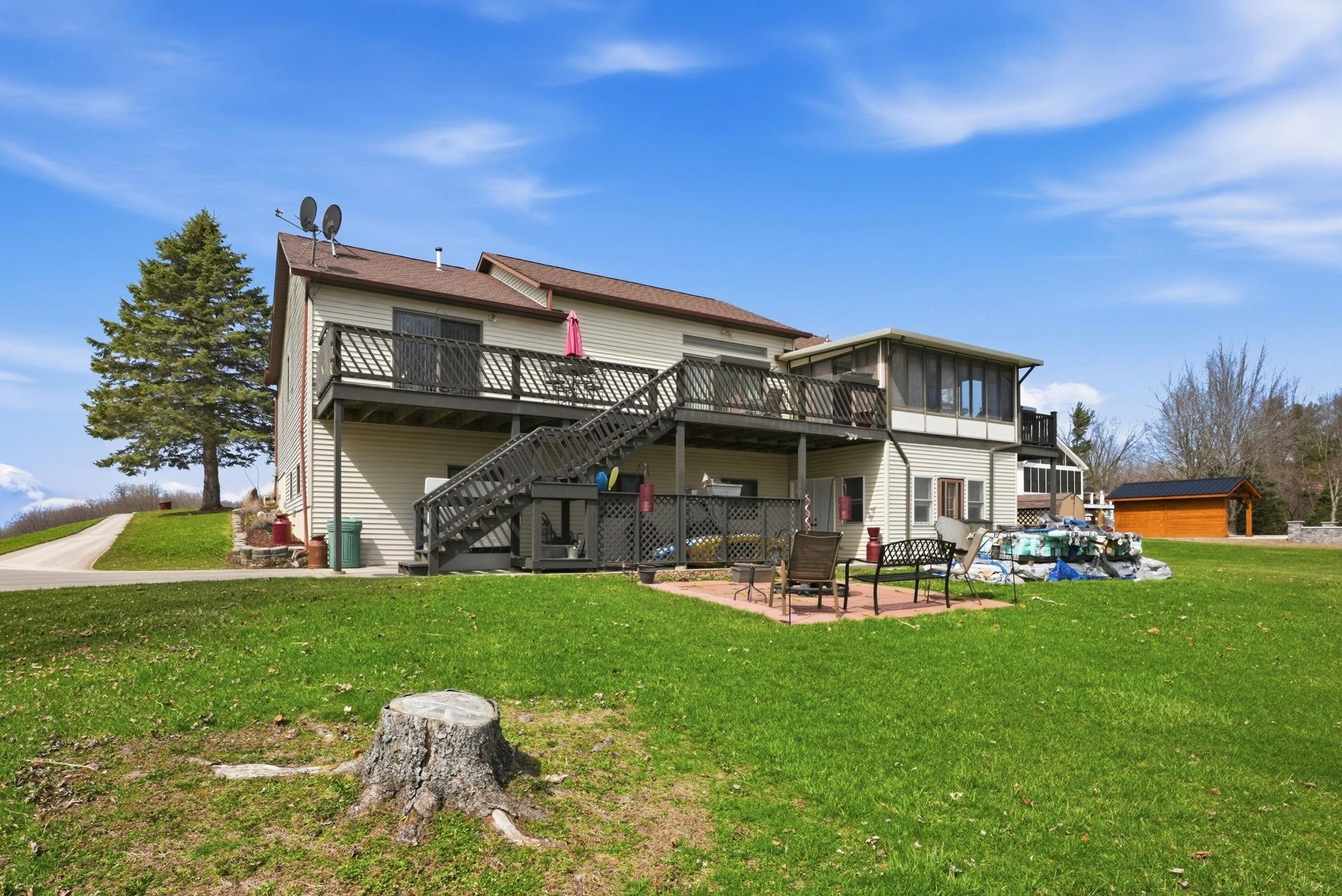 Back of property featuring a patio, a wooden deck, a lawn, and a pool