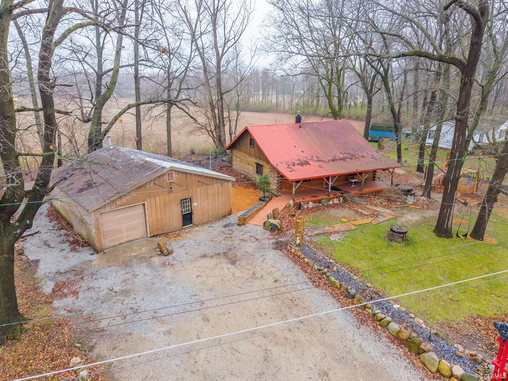 View of front of property featuring a metal roof, a front lawn, driveway, and a detached garage