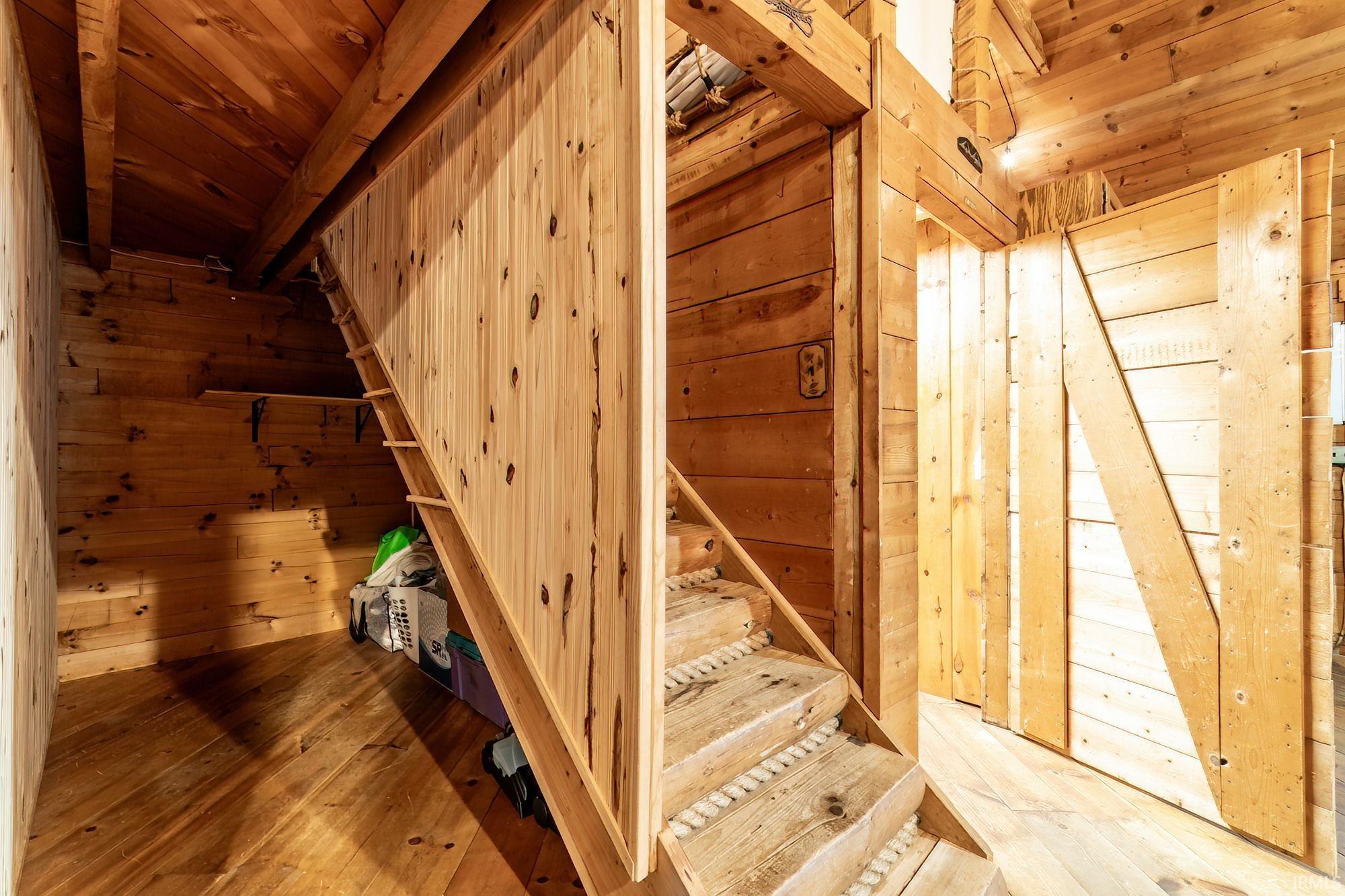 Stairs with wooden walls, hardwood / wood-style floors, and wooden ceiling