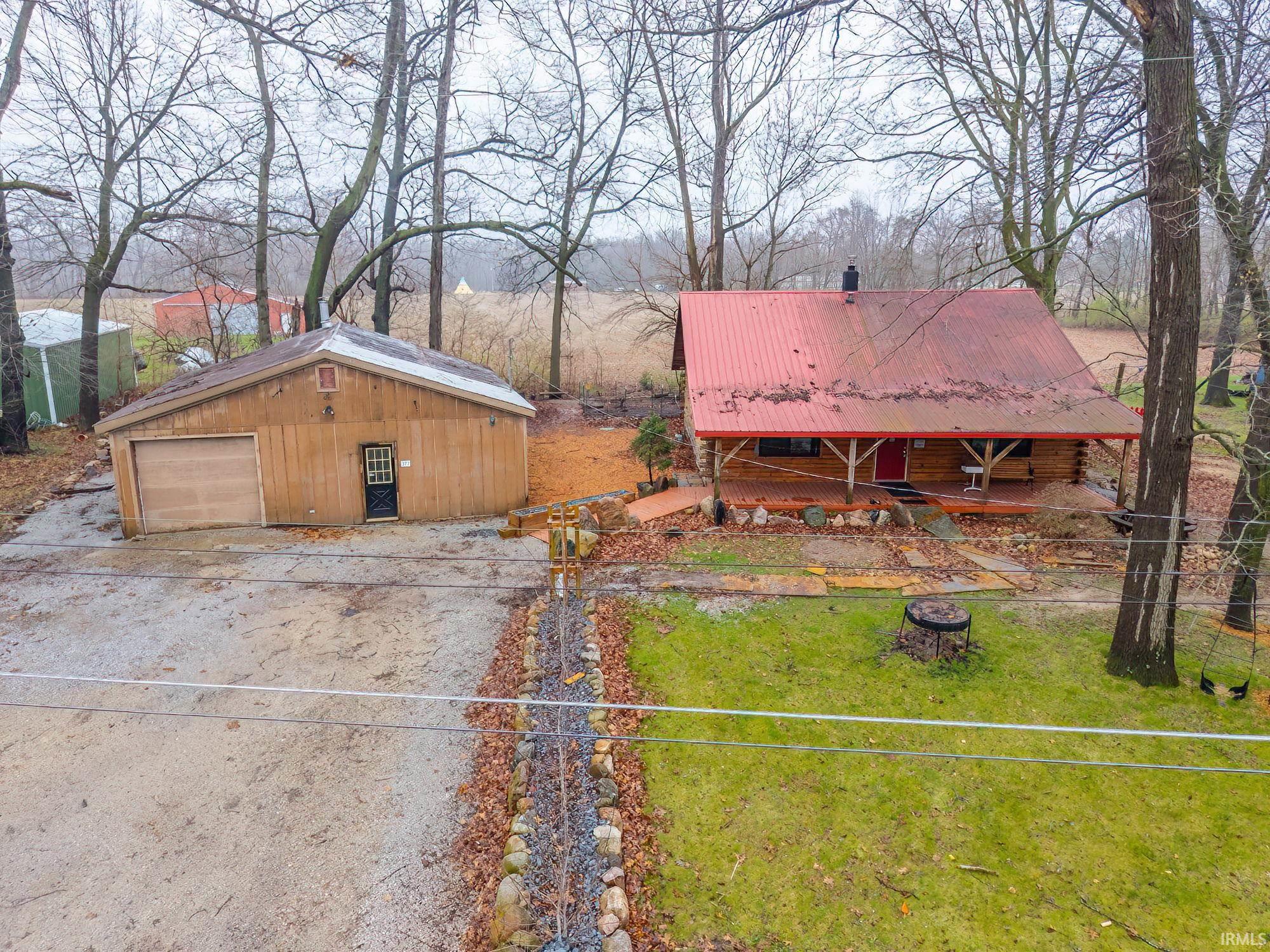 Exterior space with an outdoor structure, a metal roof, a garage, and driveway