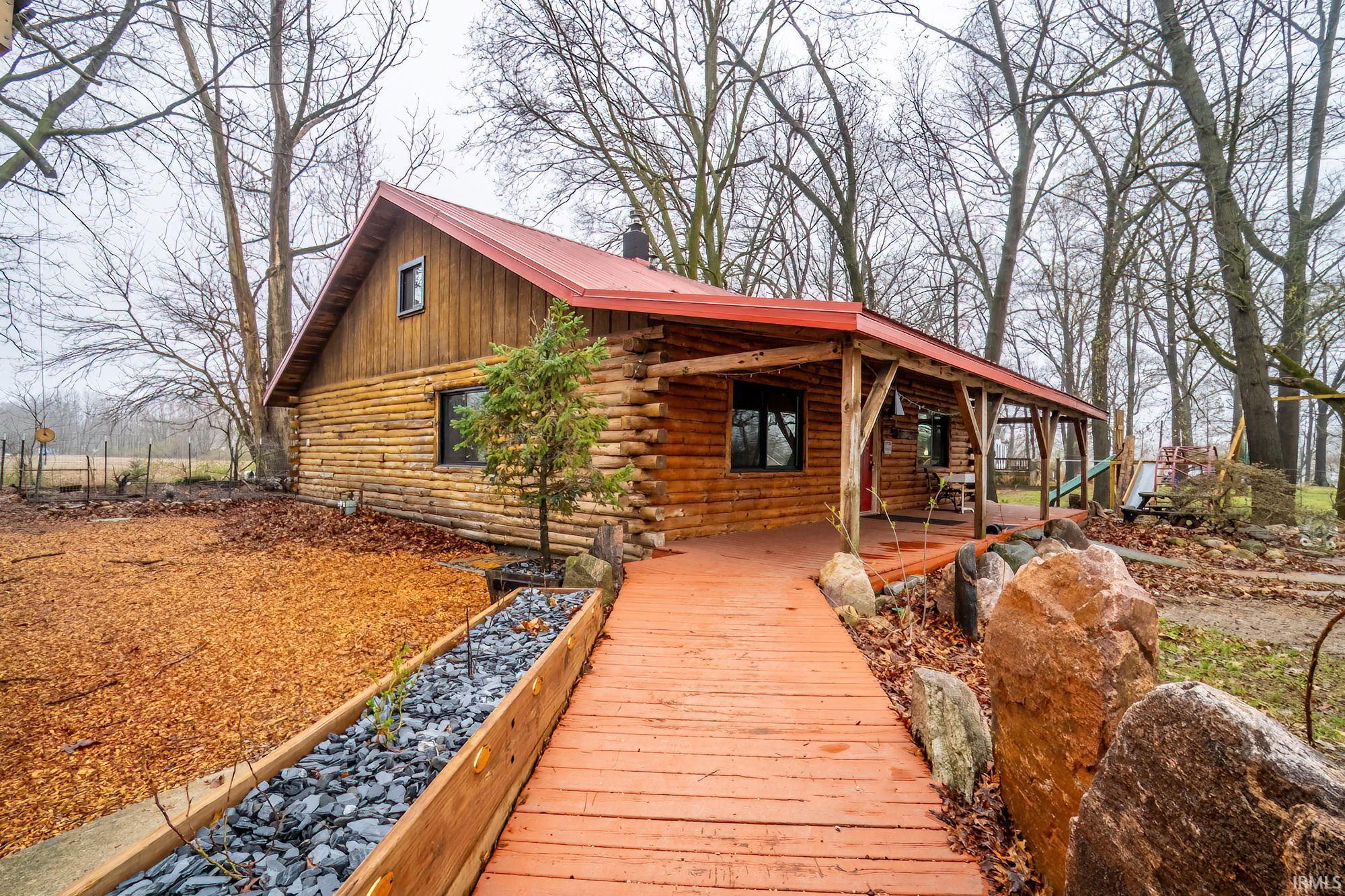 Exterior space with log exterior, a metal roof, and a porch
