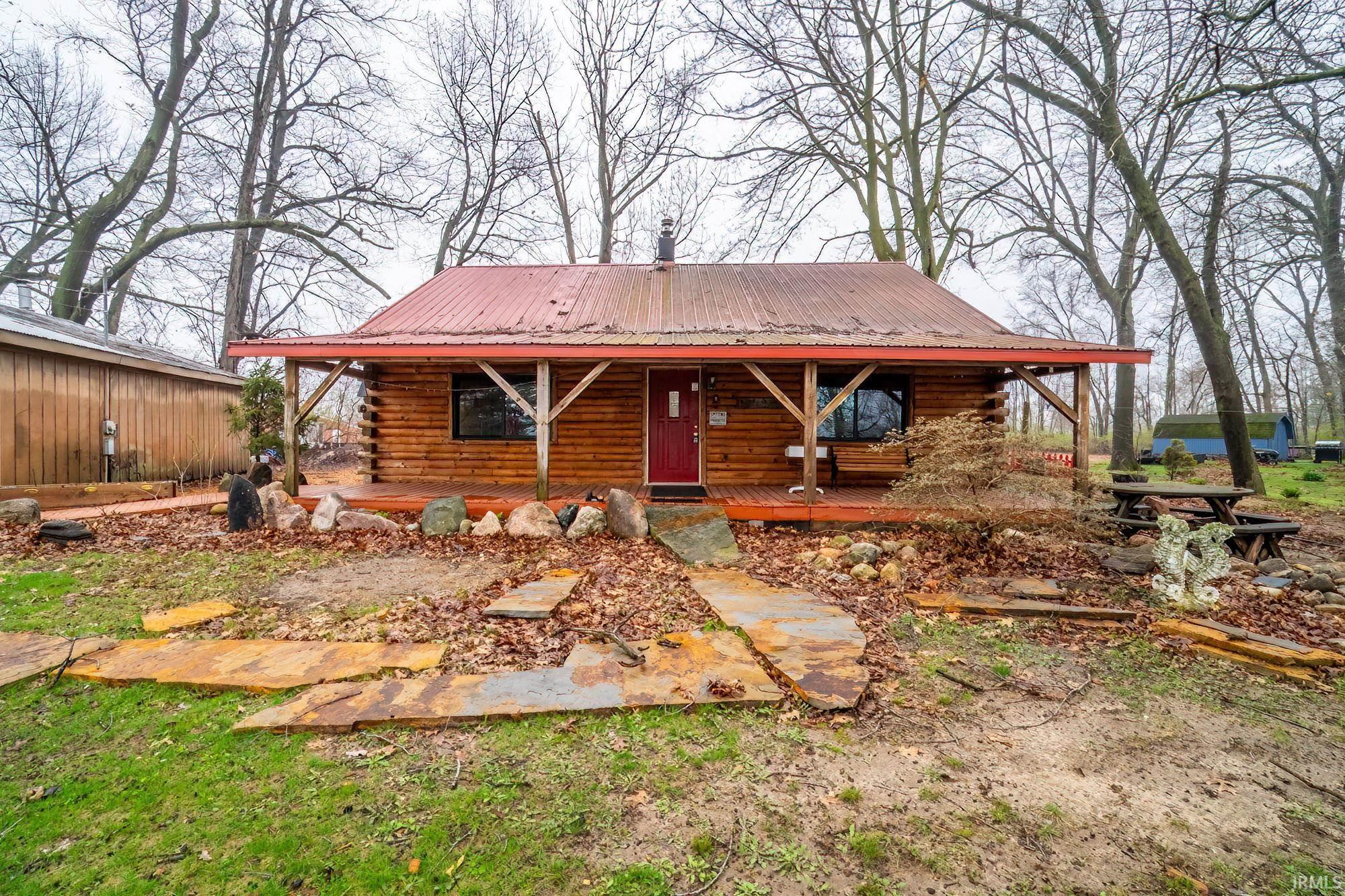 View of front of property with log siding, a metal roof, and covered porch
