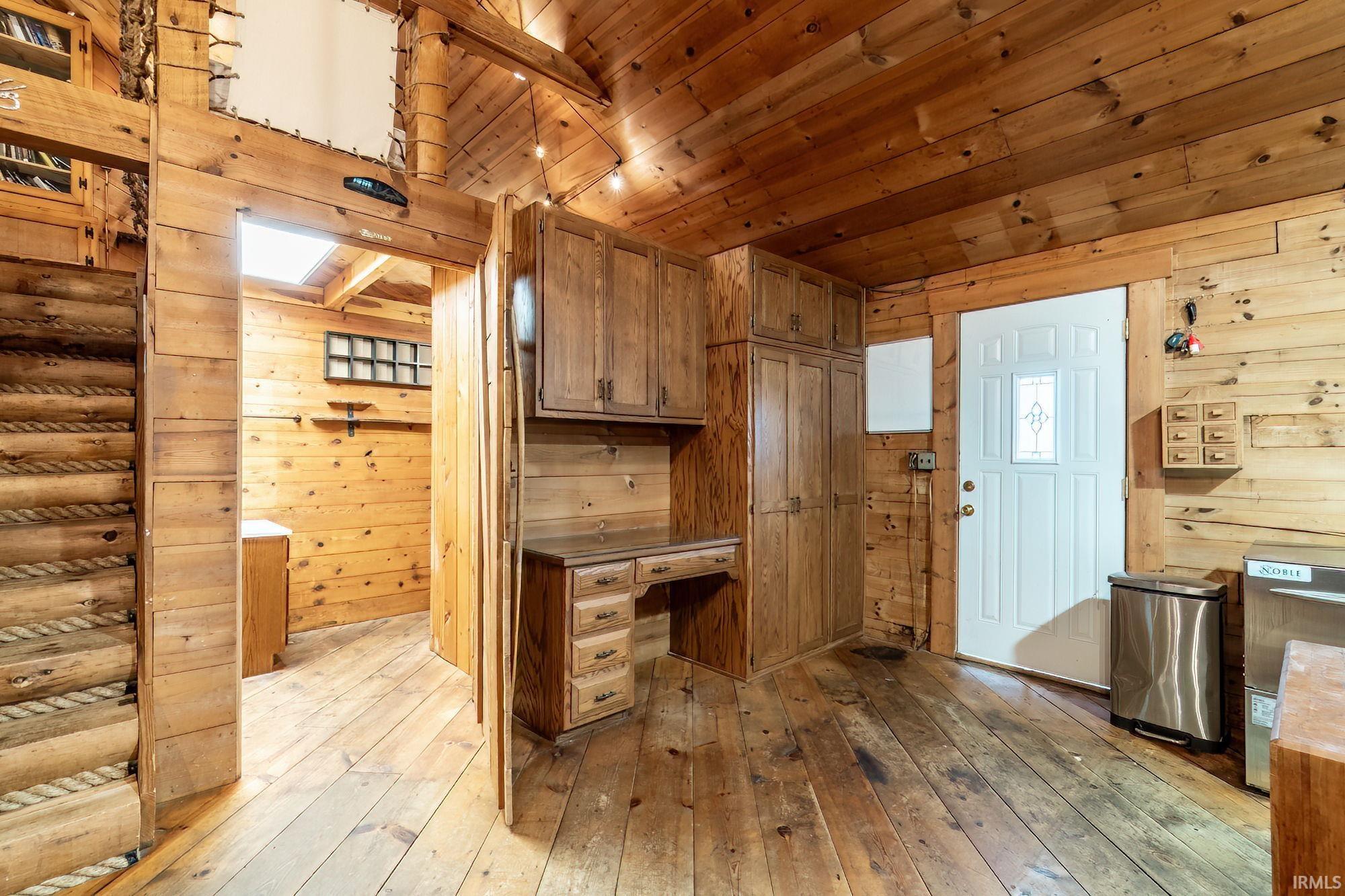 Kitchen featuring wooden walls, light wood-style flooring, wood finish cabinets, and wood ceiling