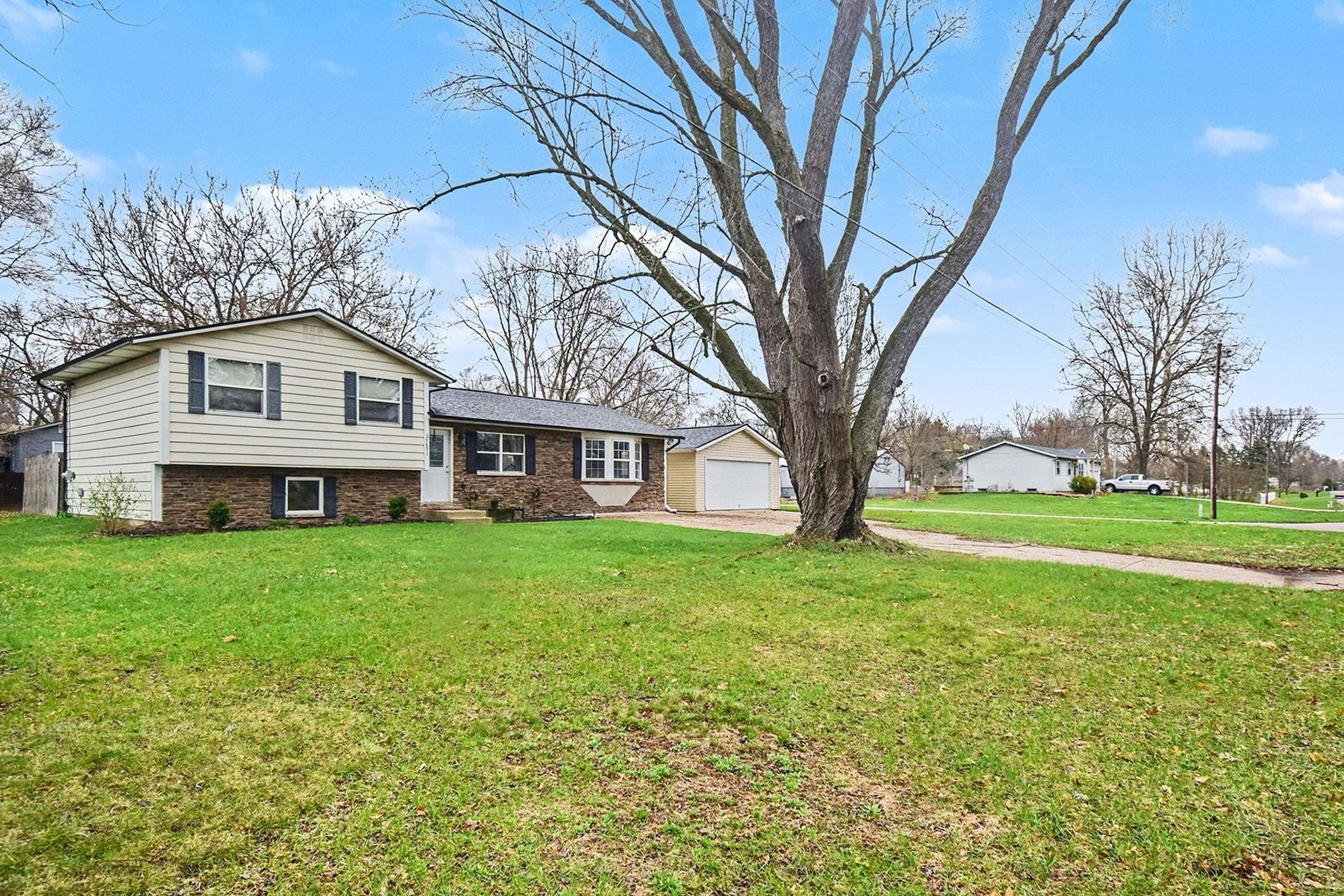 Split level home featuring a front lawn, brick siding, and driveway