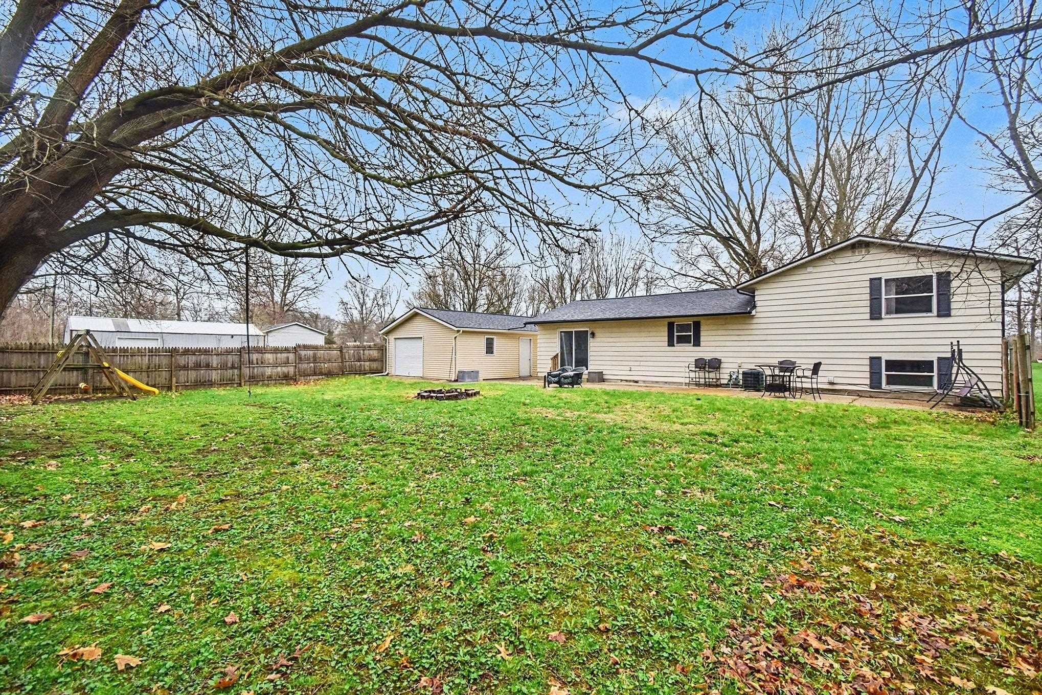 Rear view of house with a patio, a fire pit, a fenced backyard, and a garage