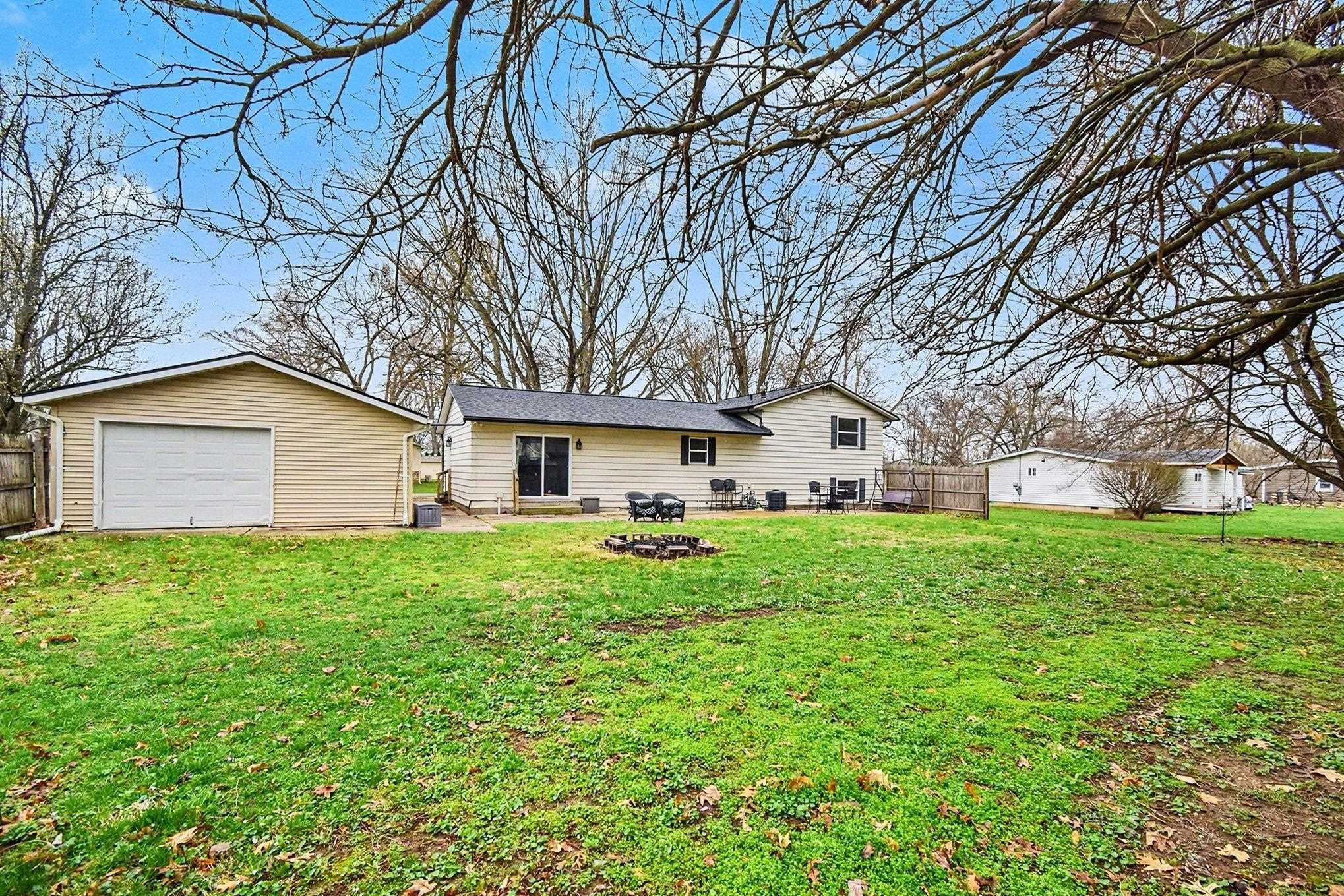 Back of property with an outbuilding, a fire pit, and a garage