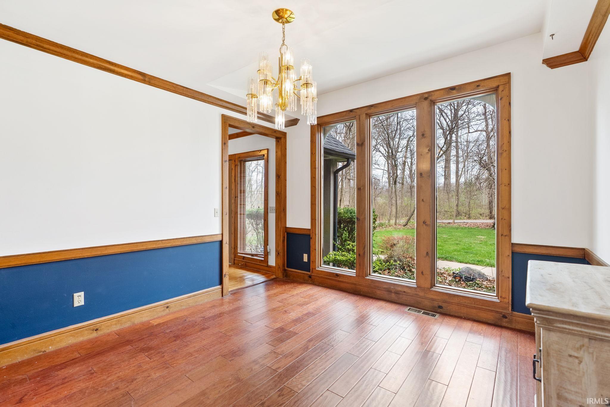 Empty room featuring hanging lights, wood finished floors, and crown molding