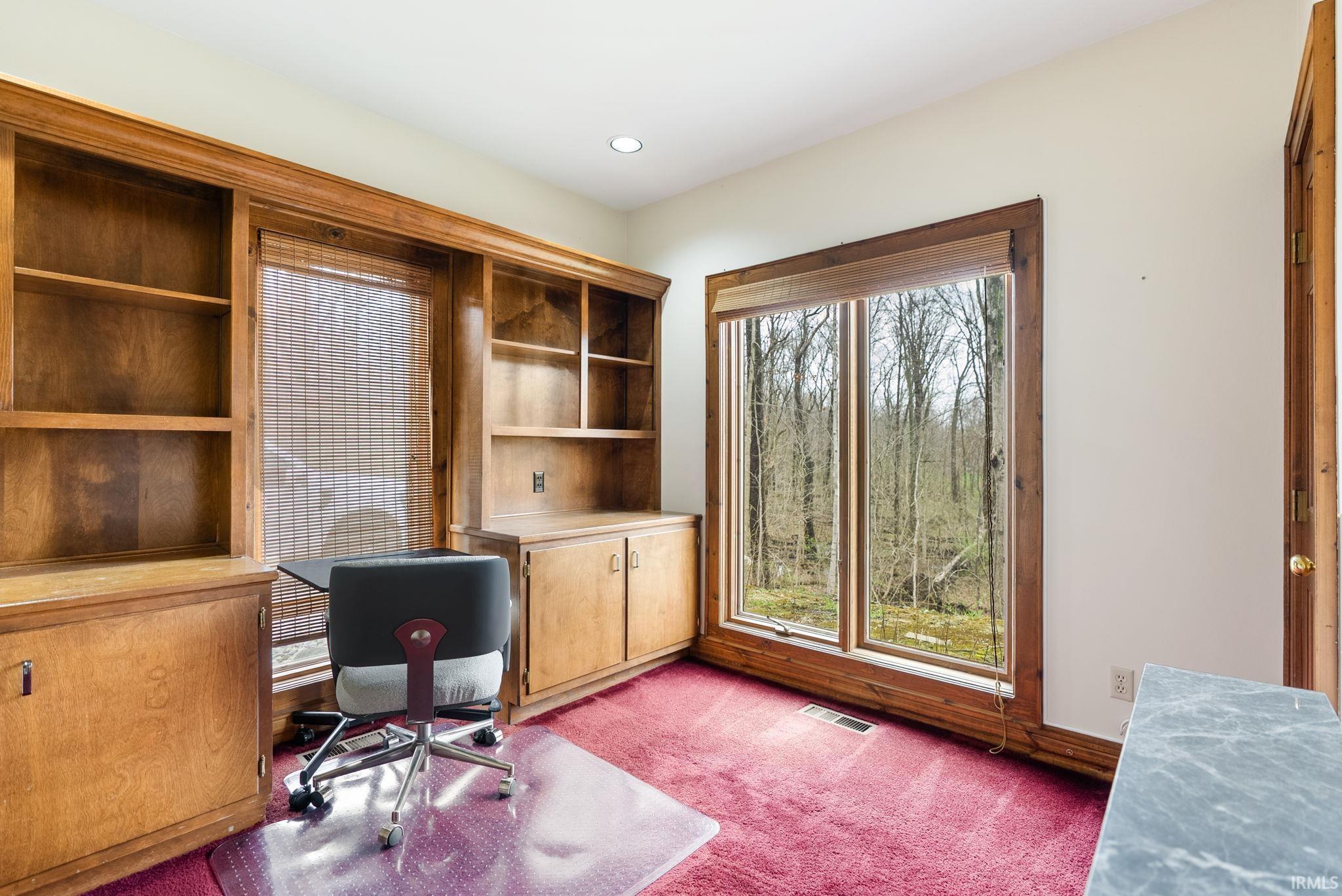 Home office with light colored carpet and recessed lighting