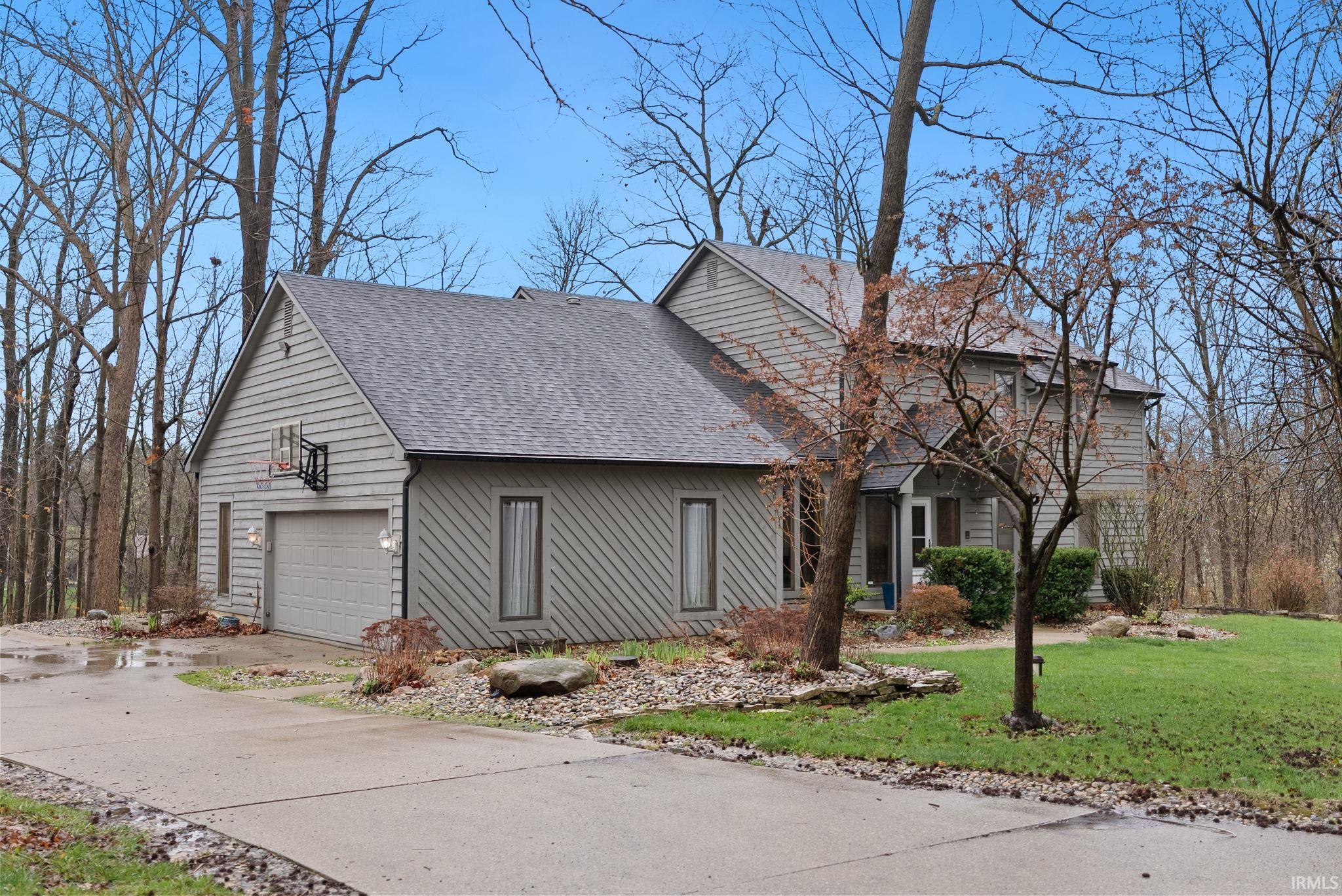 View of front facade with a shingled roof, a front lawn, driveway, and an attached garage