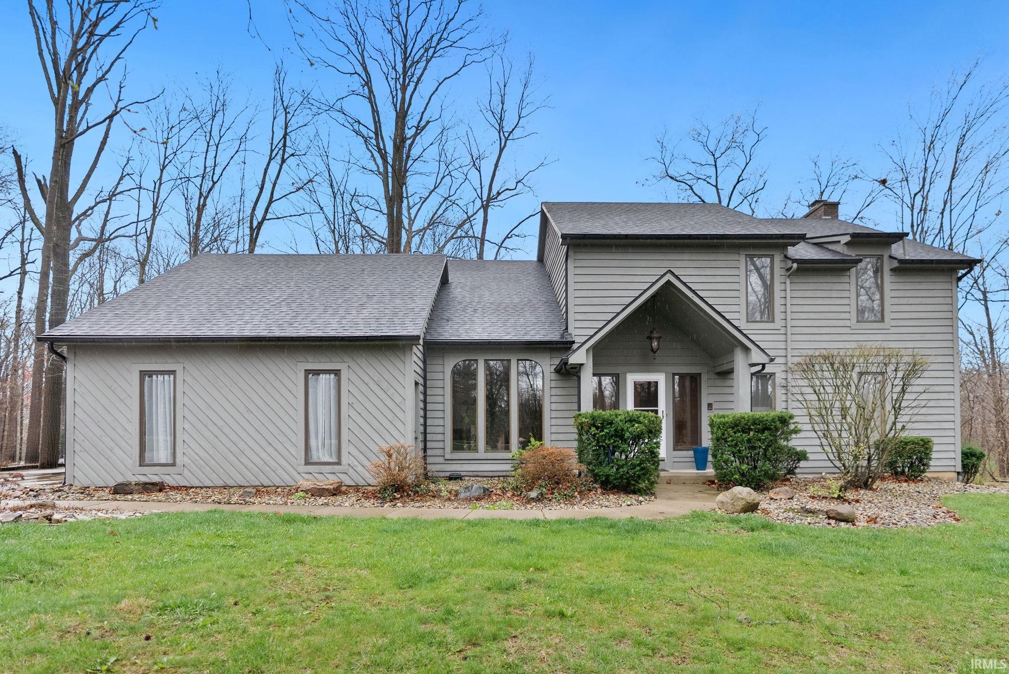 View of front of home featuring a front lawn, a chimney, and a shingled roof
