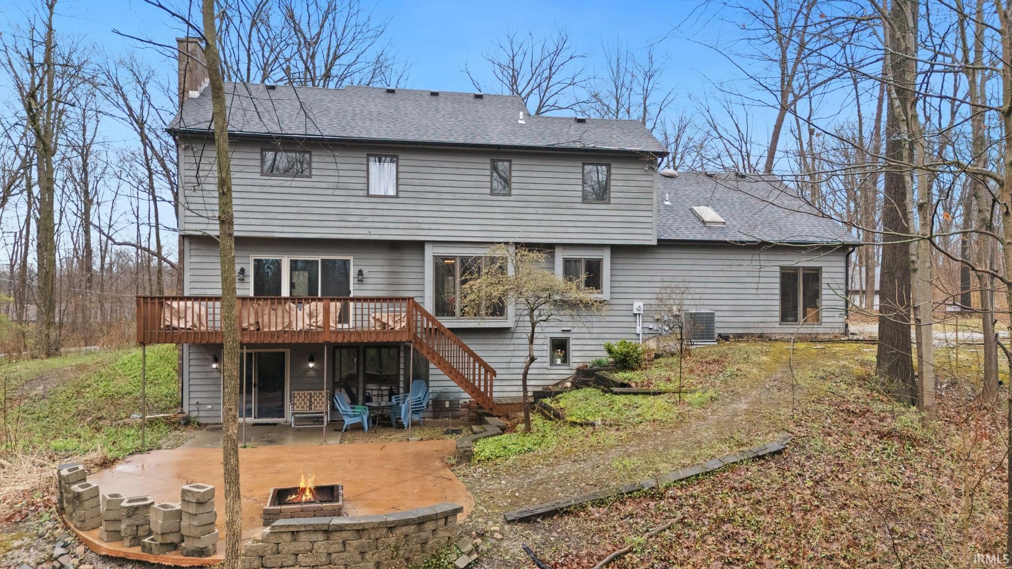 Back of house featuring a patio area, a shingled roof, a chimney, a deck, and an outdoor fire pit