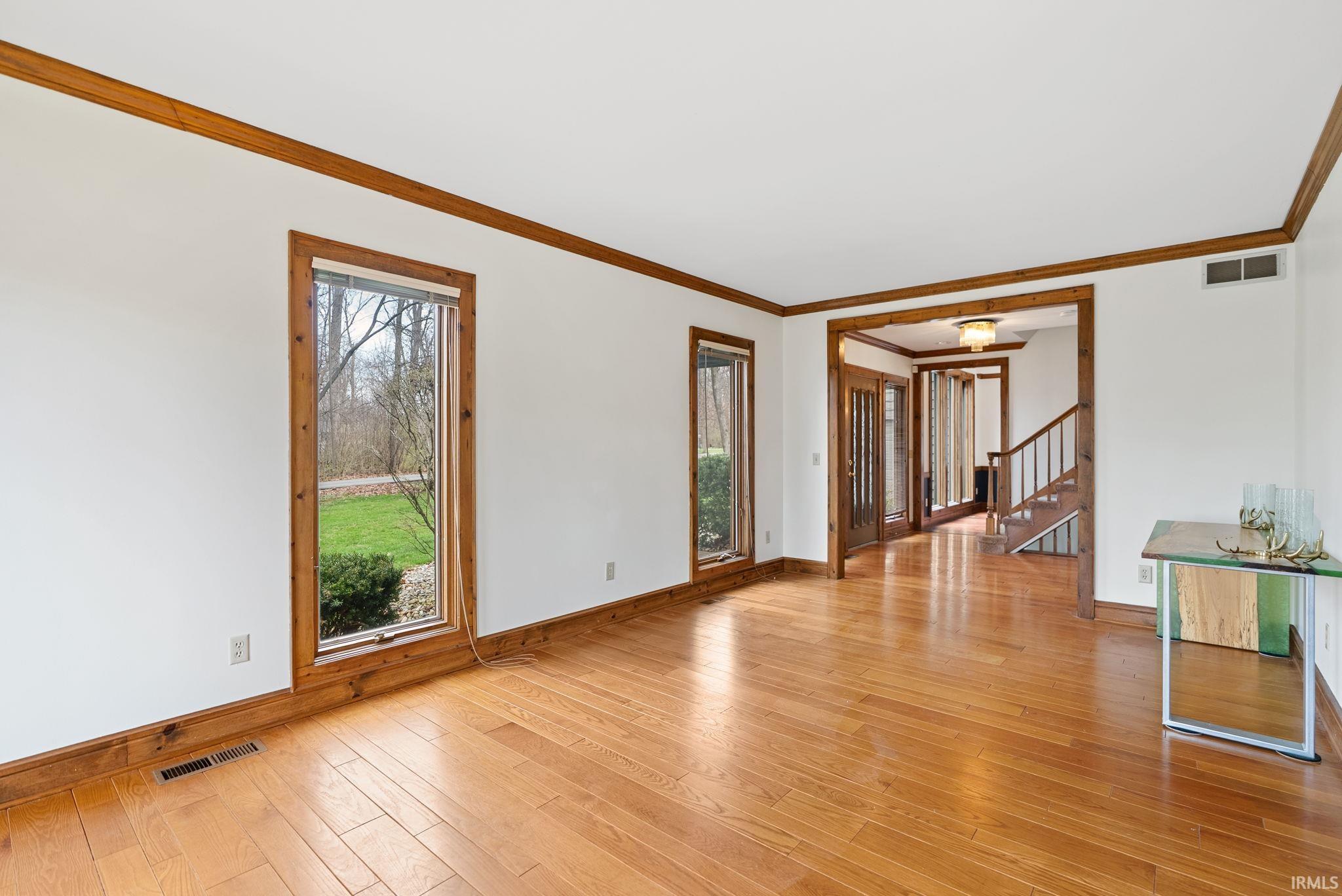 Unfurnished living room featuring ornamental molding and light wood-style flooring