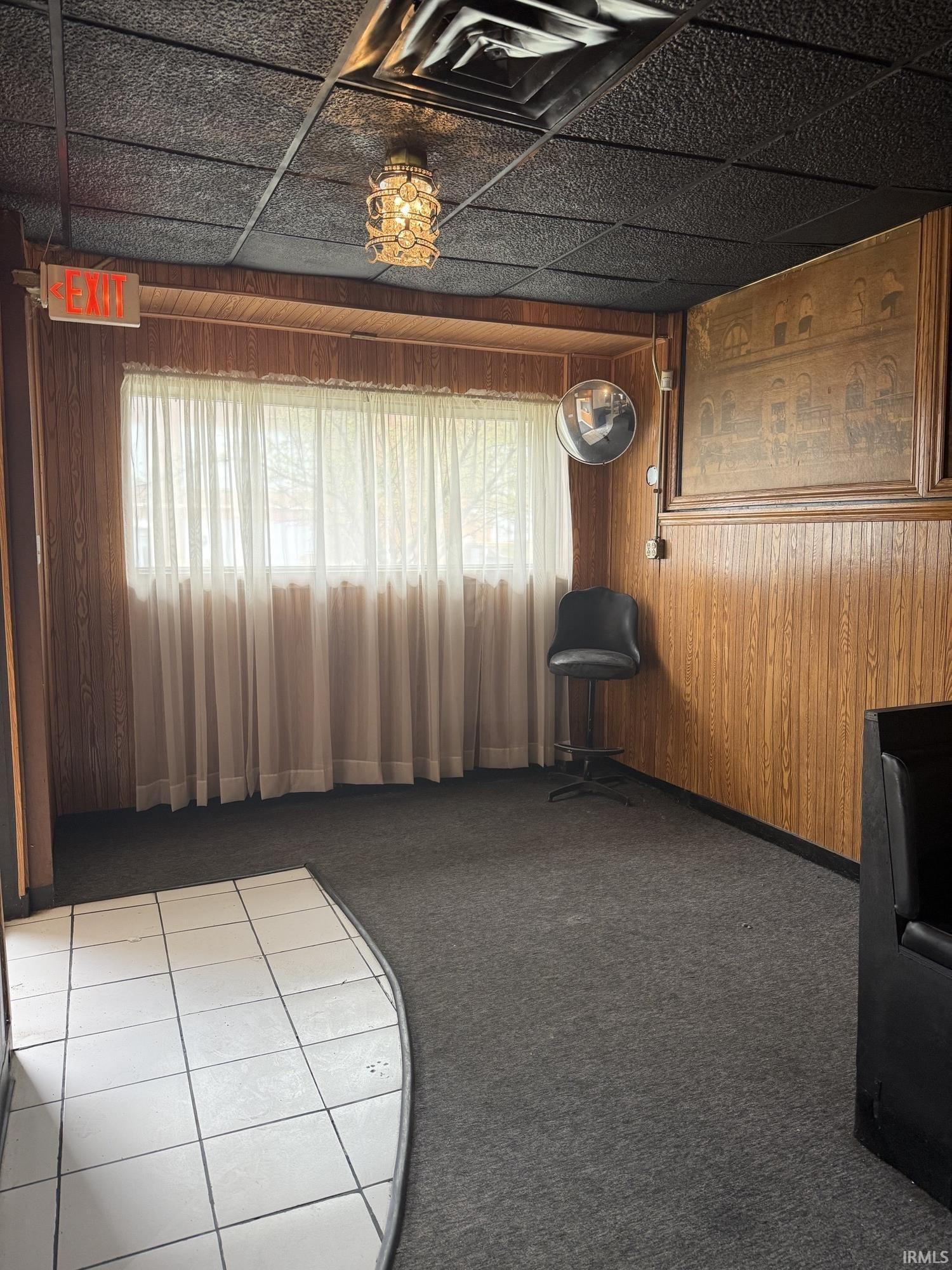 Living area featuring wooden walls, carpet, and tile patterned floors