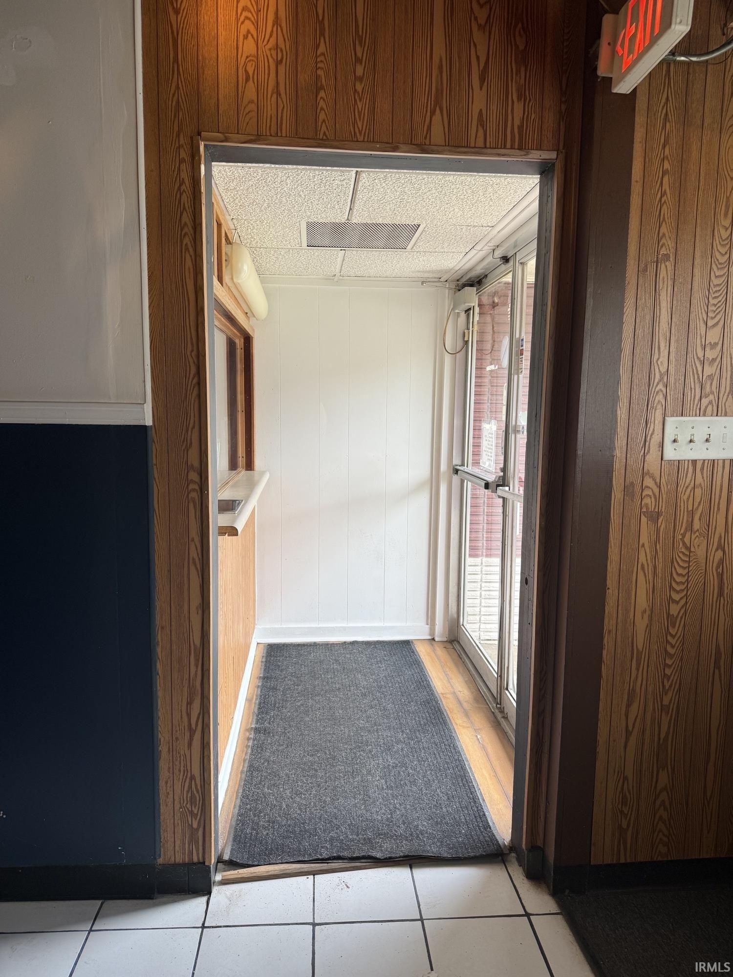 Hall with wooden walls and light tile patterned floors