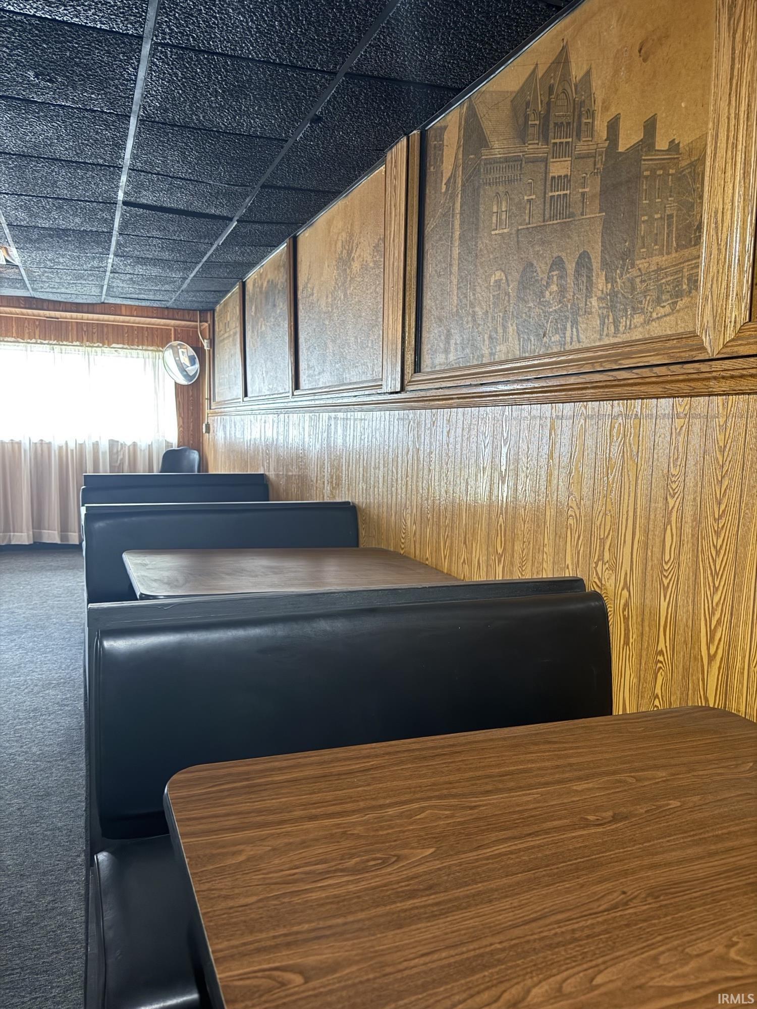 Carpeted dining room featuring wooden walls