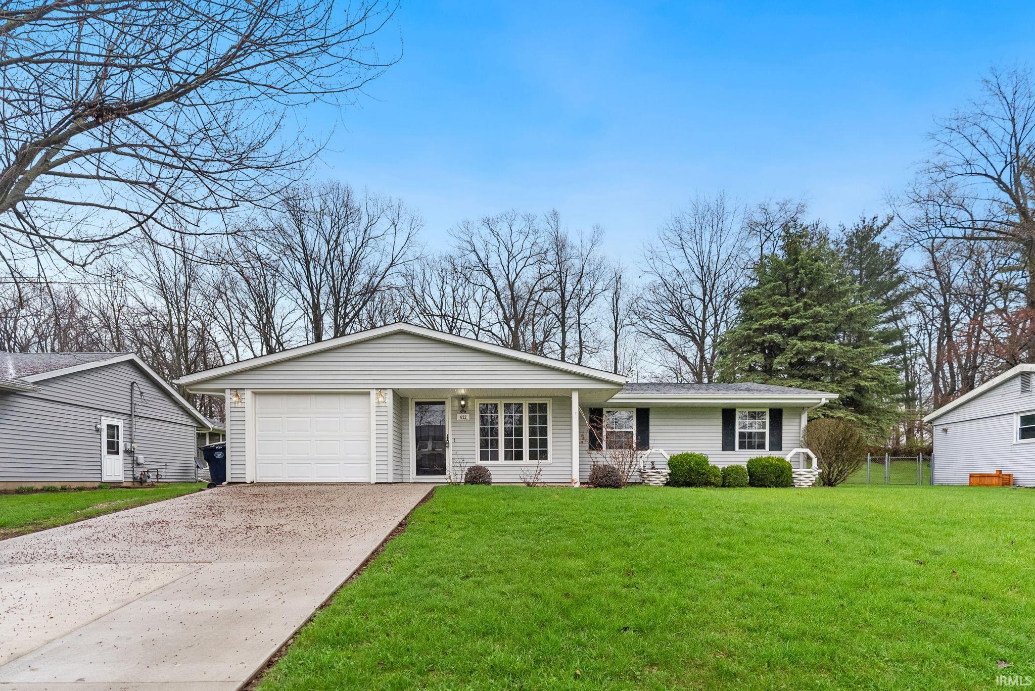 Ranch-style home with a front lawn, a garage, and driveway